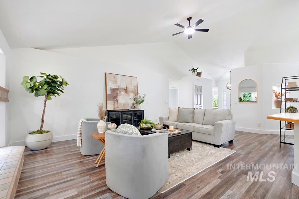 Living area featuring light wood-type flooring, ceiling fan, and high vaulted ceiling
