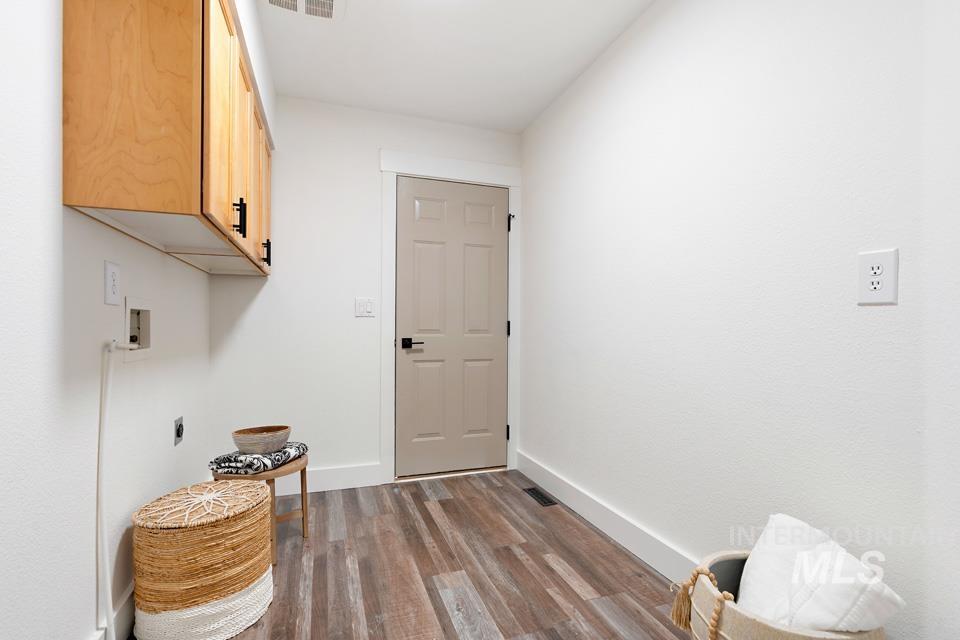 Laundry room with dark wood-style floors, cabinet space, and electric dryer hookup