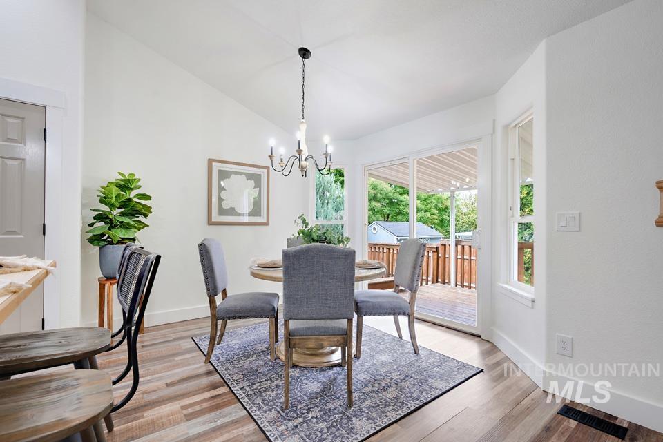 Dining space featuring light wood-style floors, vaulted ceiling, and a chandelier