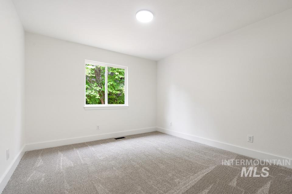 Unfurnished room featuring light carpet and baseboards
