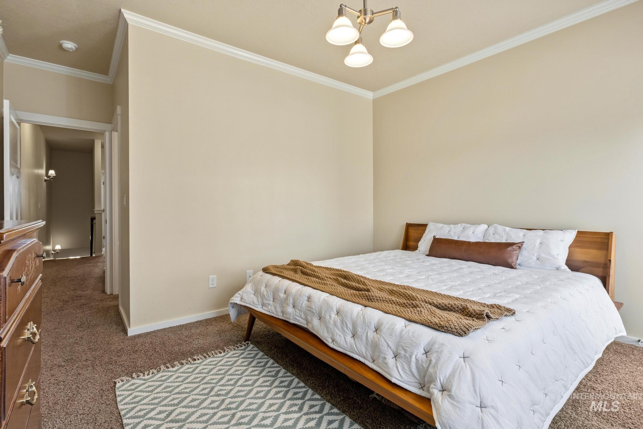 Bedroom with carpet, crown molding, and suspended lighting