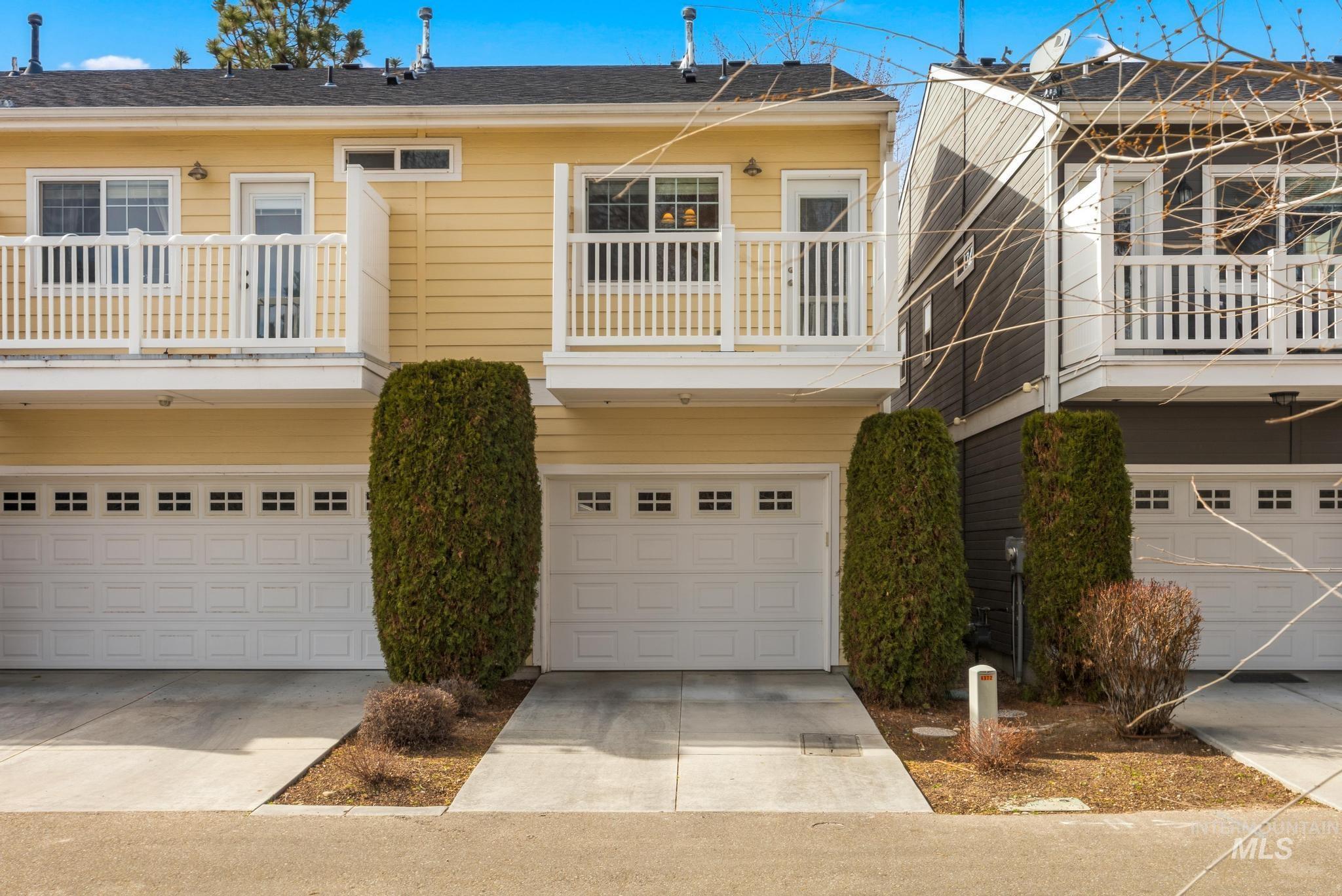 View of front of property with a balcony, driveway, and a garage