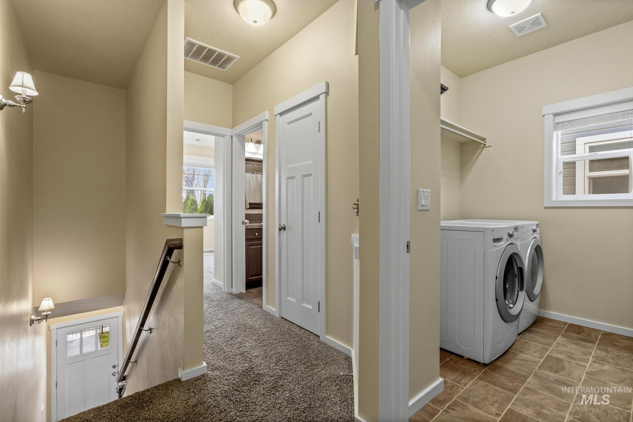Laundry room with washing machine and dryer and dark colored carpet