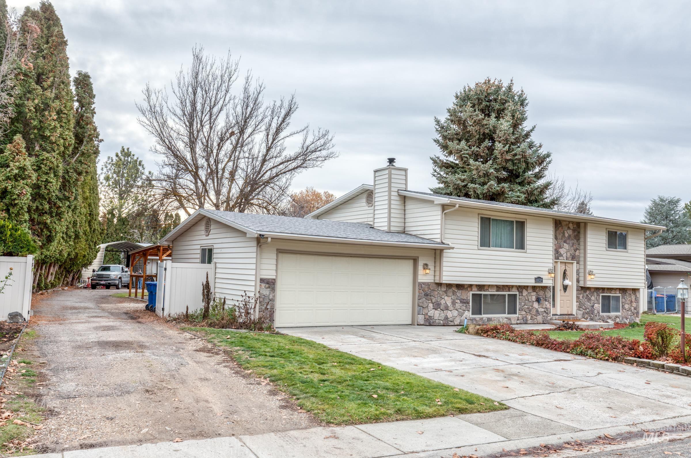 View of front facade with concrete driveway, stone siding, an attached garage, and a chimney
