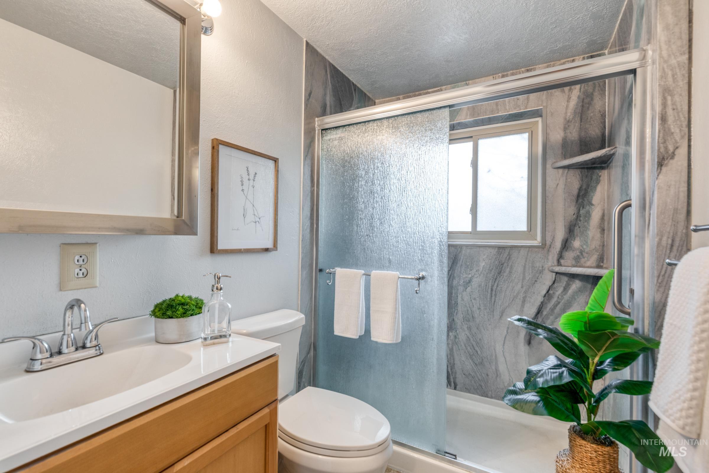 Full bathroom with vanity, a shower stall, and a textured ceiling