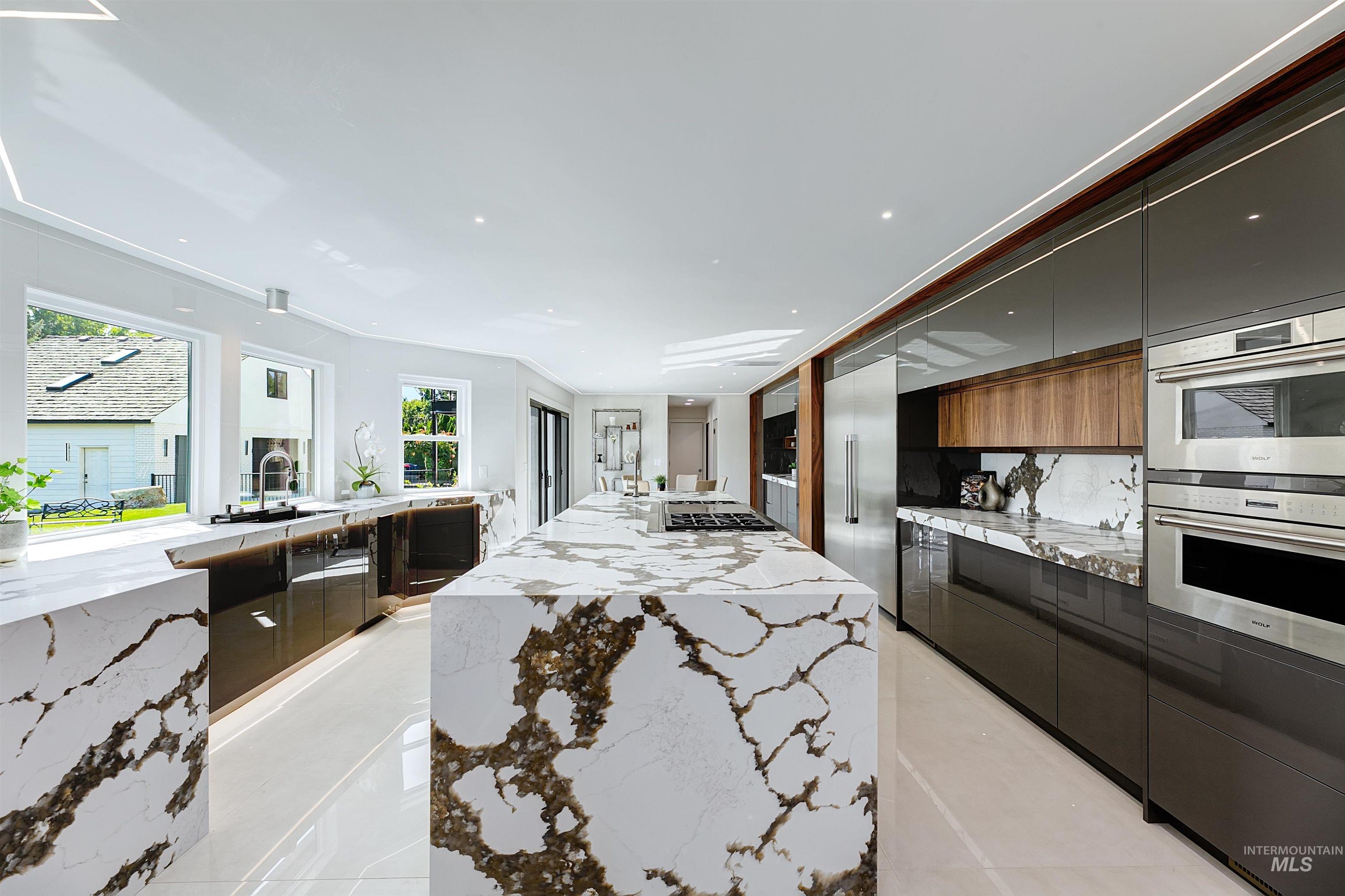 Kitchen featuring quartzite waterfall countertops, modern cabinets, and ornamental molding.