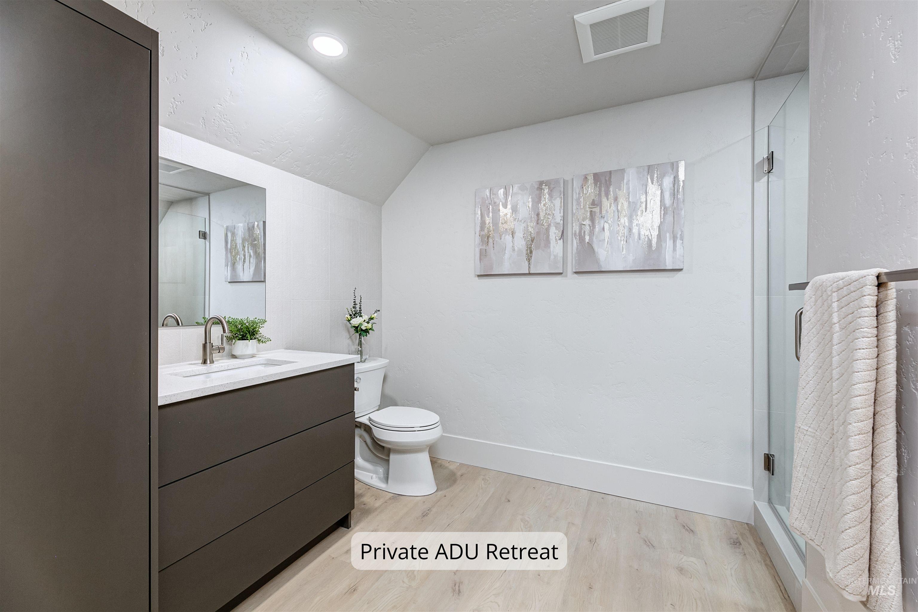 Private ADU bathroom with light wood-type flooring, vanity, and a tiled shower.