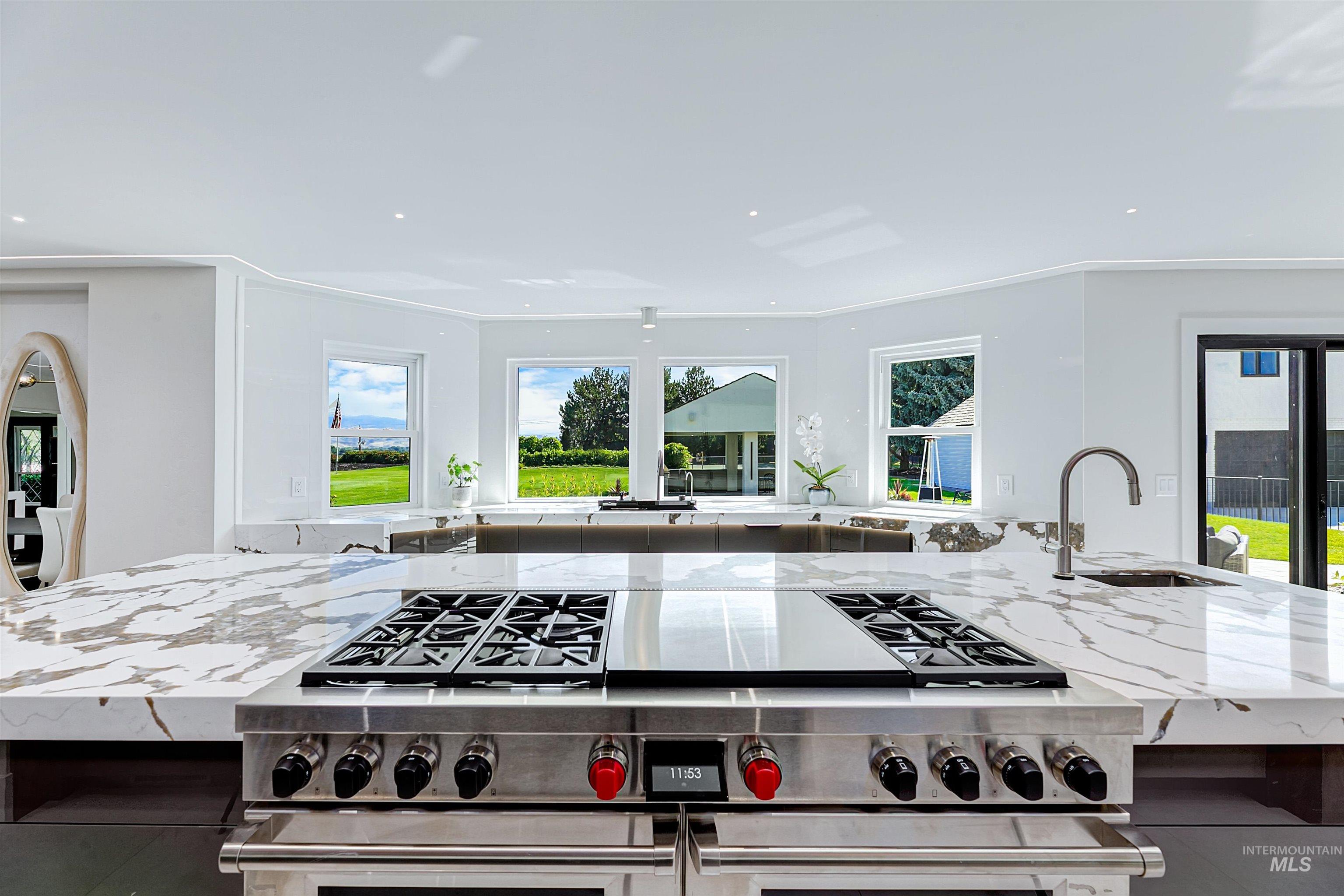 Kitchen with quartzite countertops, double oven range, a center island, plenty of natural light, and recessed lighting.
