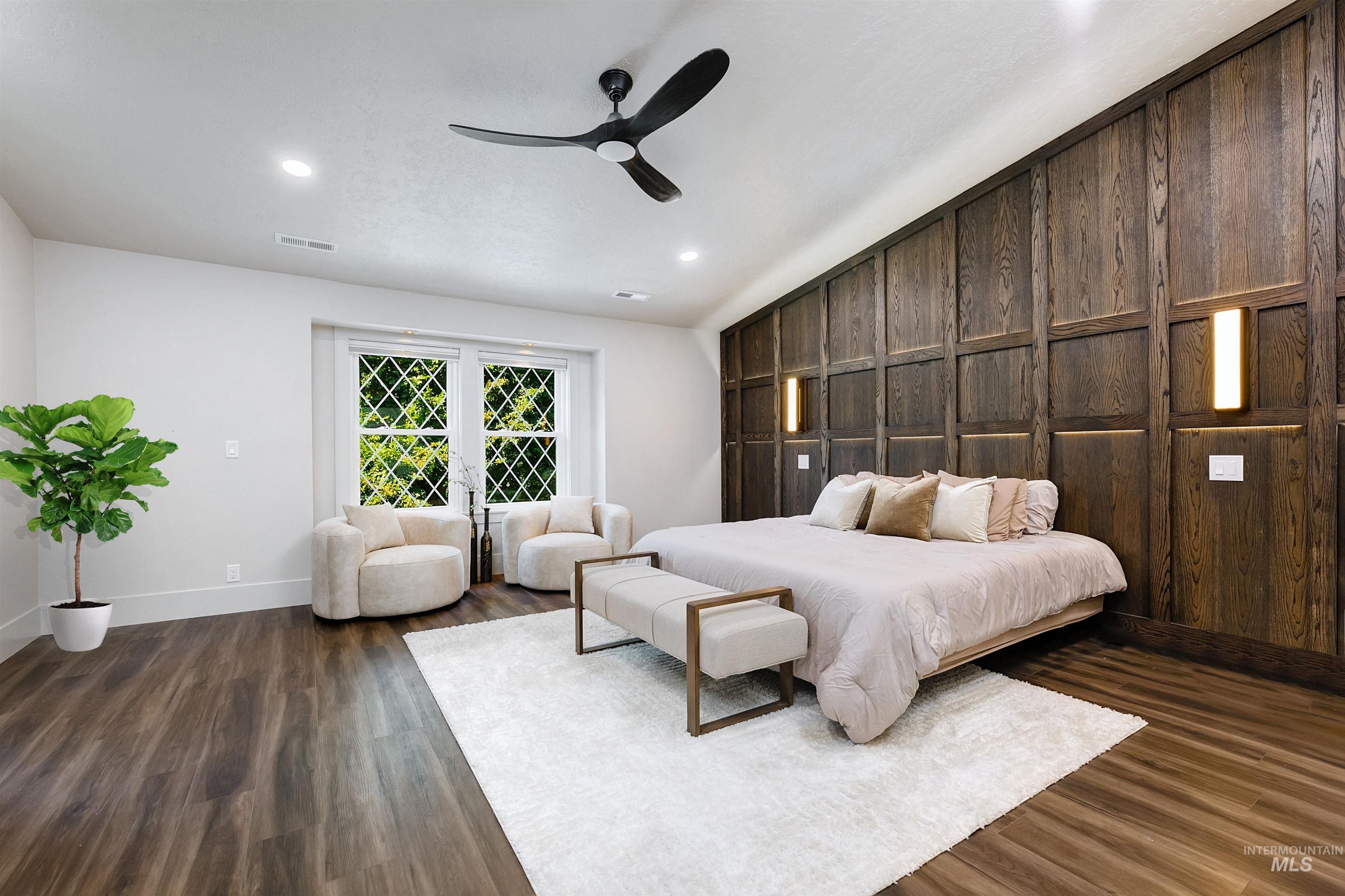 Master bedroom featuring a ceiling fan, dark wood-style floors, and a wooden wall accent.