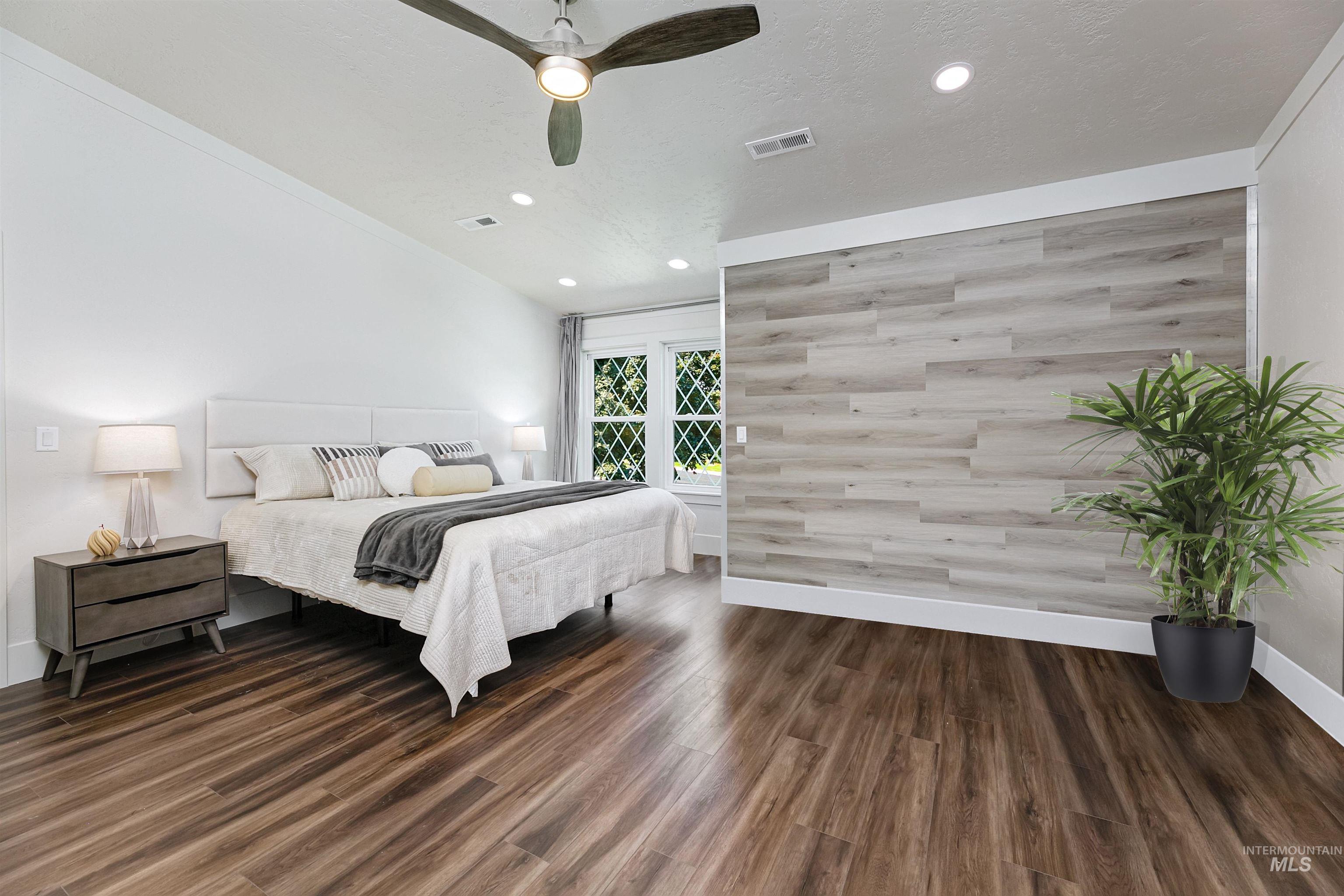 Bedroom with dark wood finished floors, recessed lighting, wooden walls, and a ceiling fan.