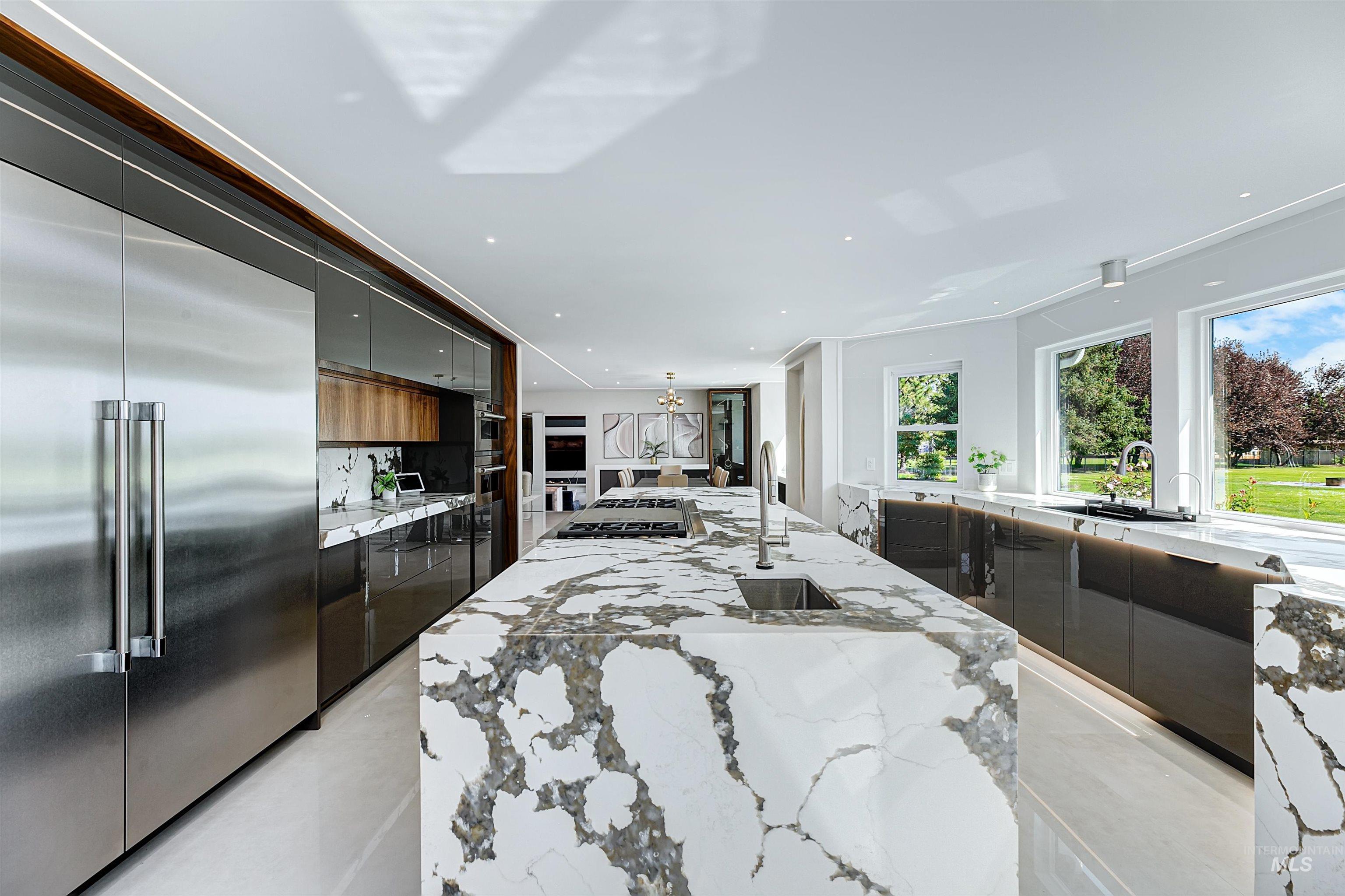 Kitchen with modern cabinets, appliances with stainless steel finishes, a spacious island, quartzite countertops, and recessed lighting.