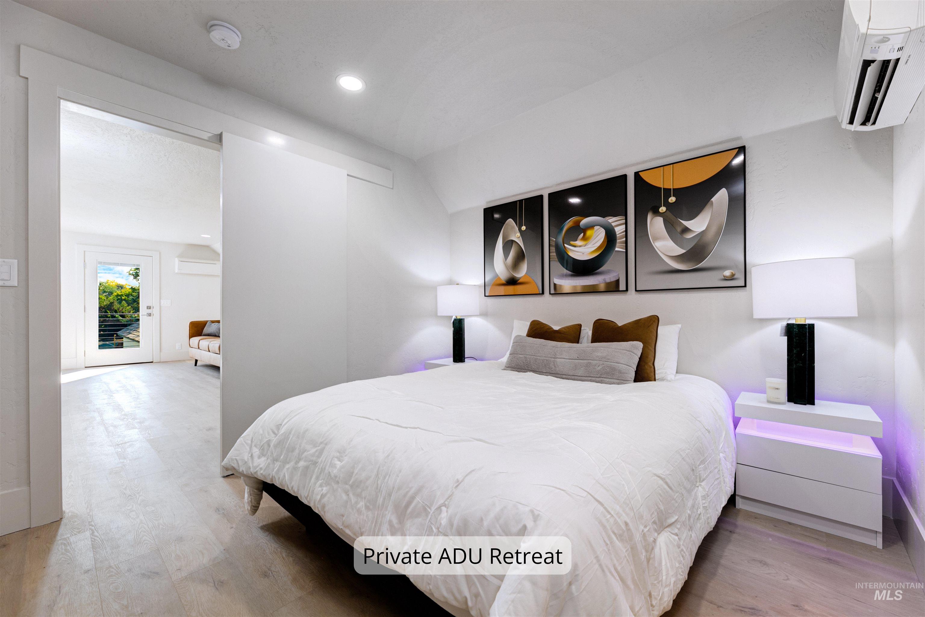 Private ADU bedroom featuring light wood-type flooring, a wall mounted AC, and recessed lighting.