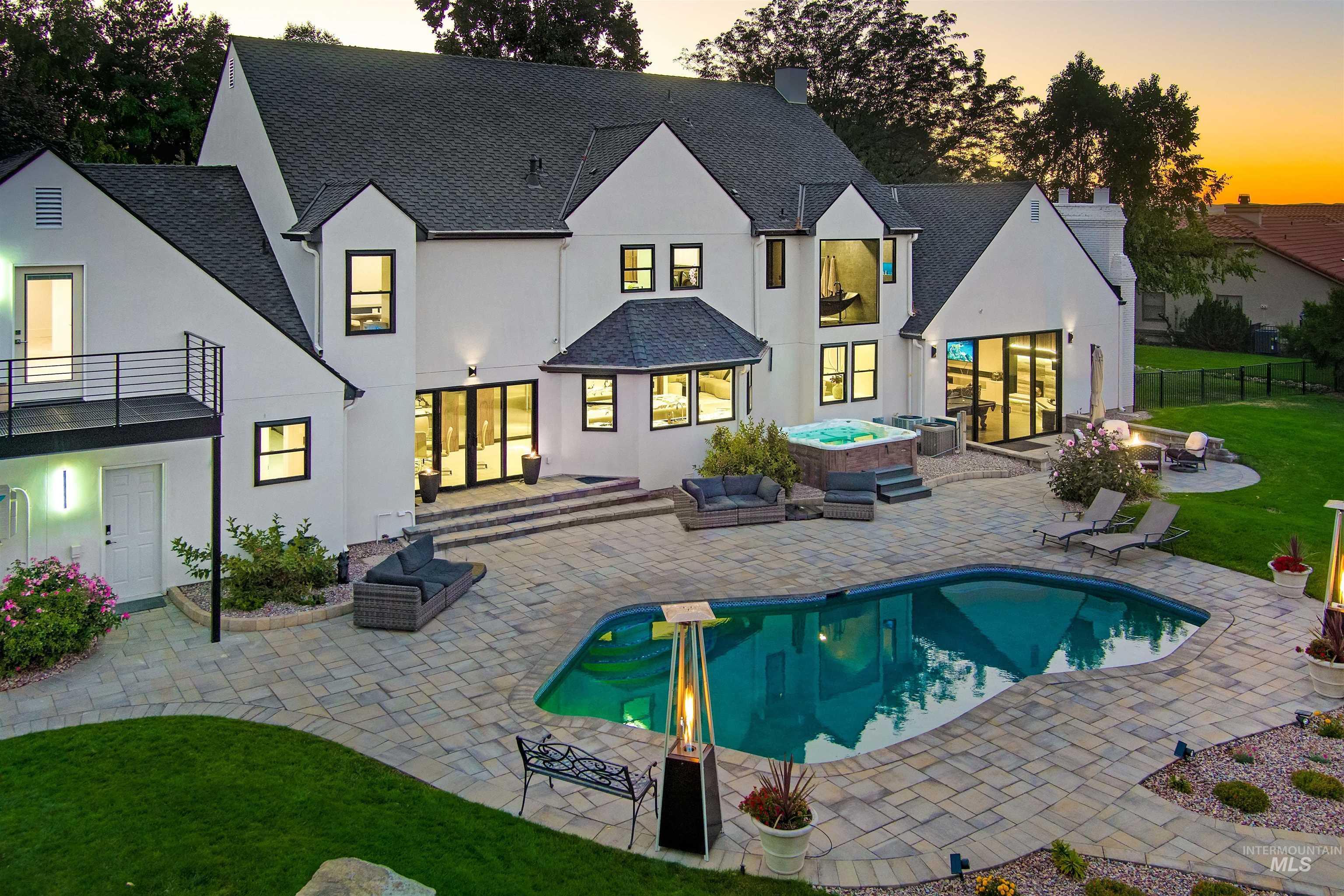 Back of house featuring stucco siding, a patio area with multiple seating areas, and a large hot tub.
