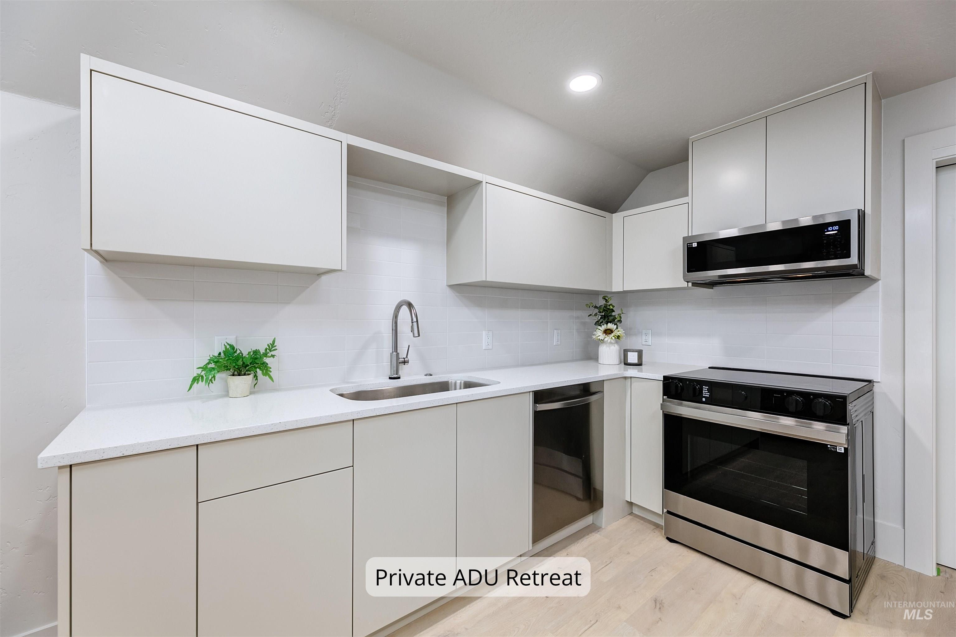 Private ADU kitchen featuring backsplash, stainless steel SAMSUNG appliances, light wood finished floors, modern cabinets, and quartz countertops.