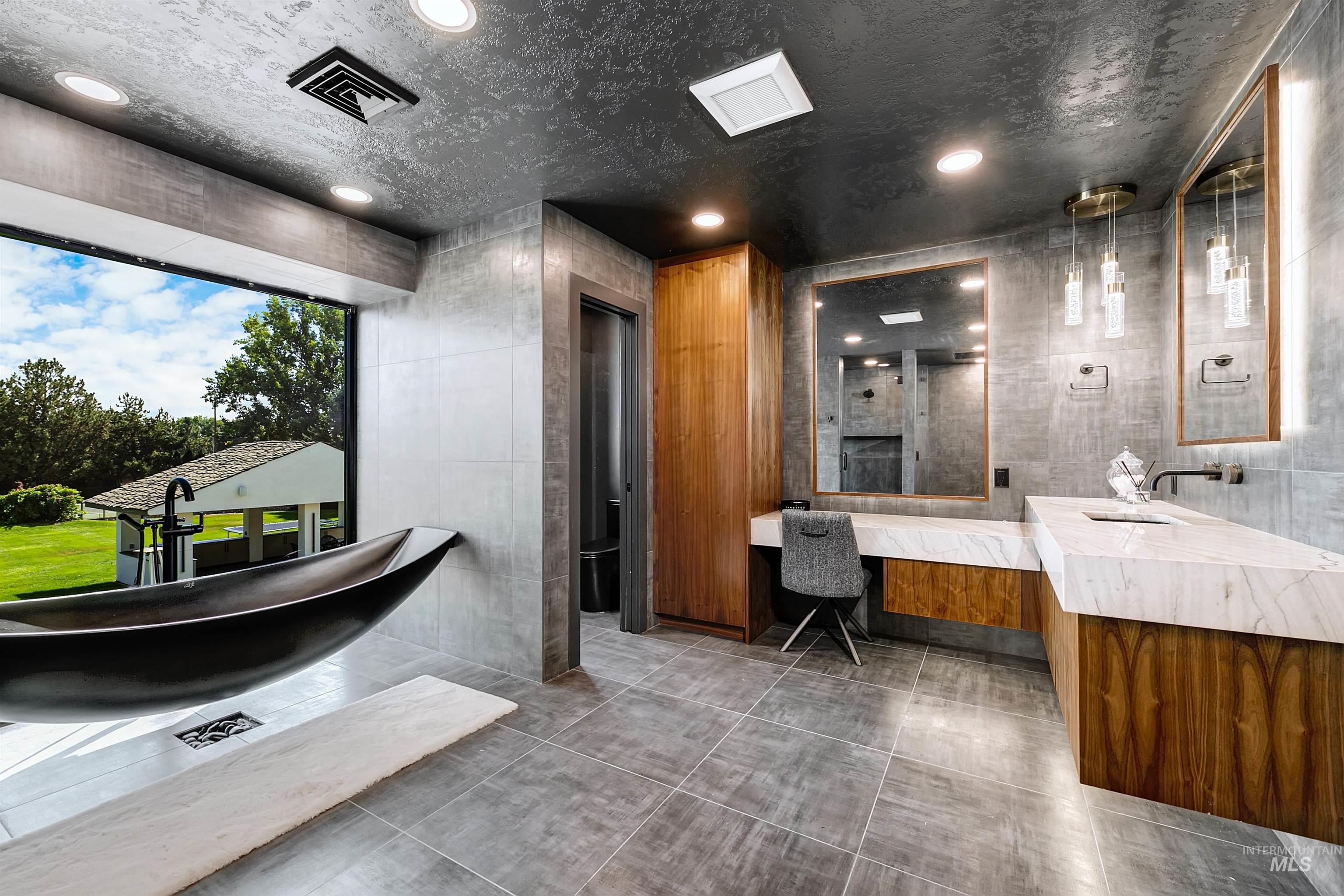 Master bathroom featuring tile walls, sitting vanity, tiled shower, and a freestanding tub.