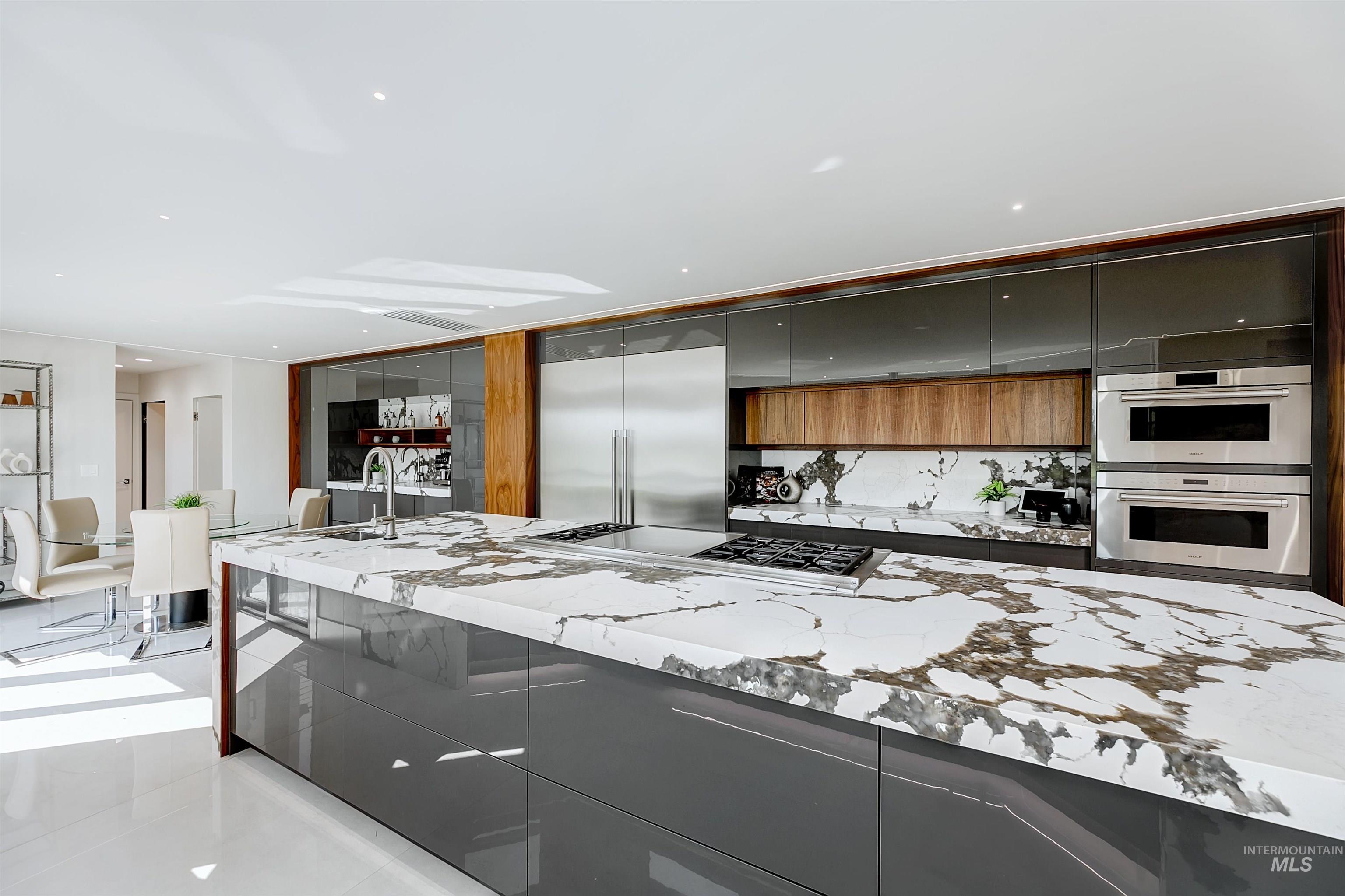 Kitchen featuring modern cabinets, quartzite countertops, appliances with stainless steel finishes, and recessed lighting.