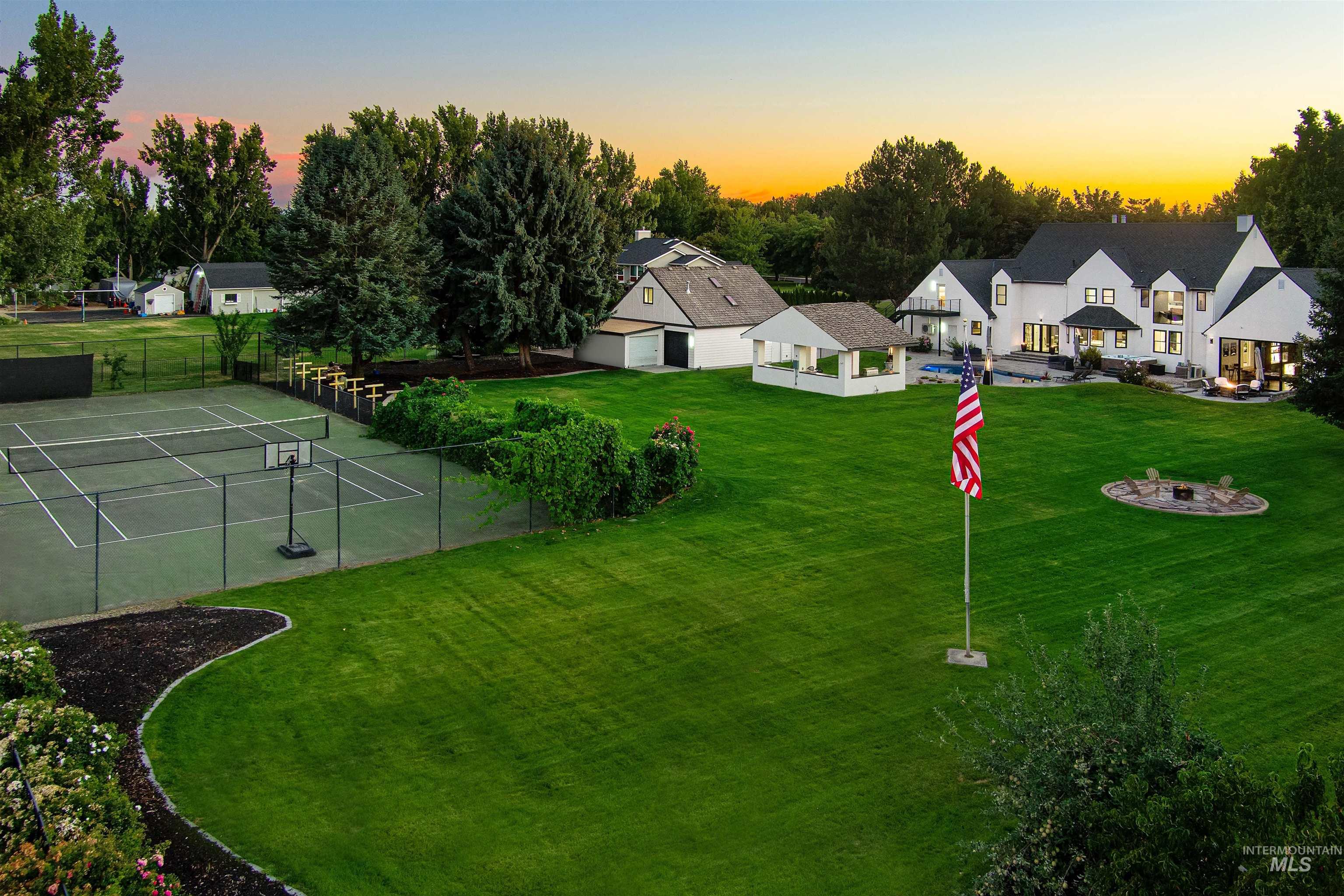 View of yard with a full size tennis court, garden area, and fire pit area.