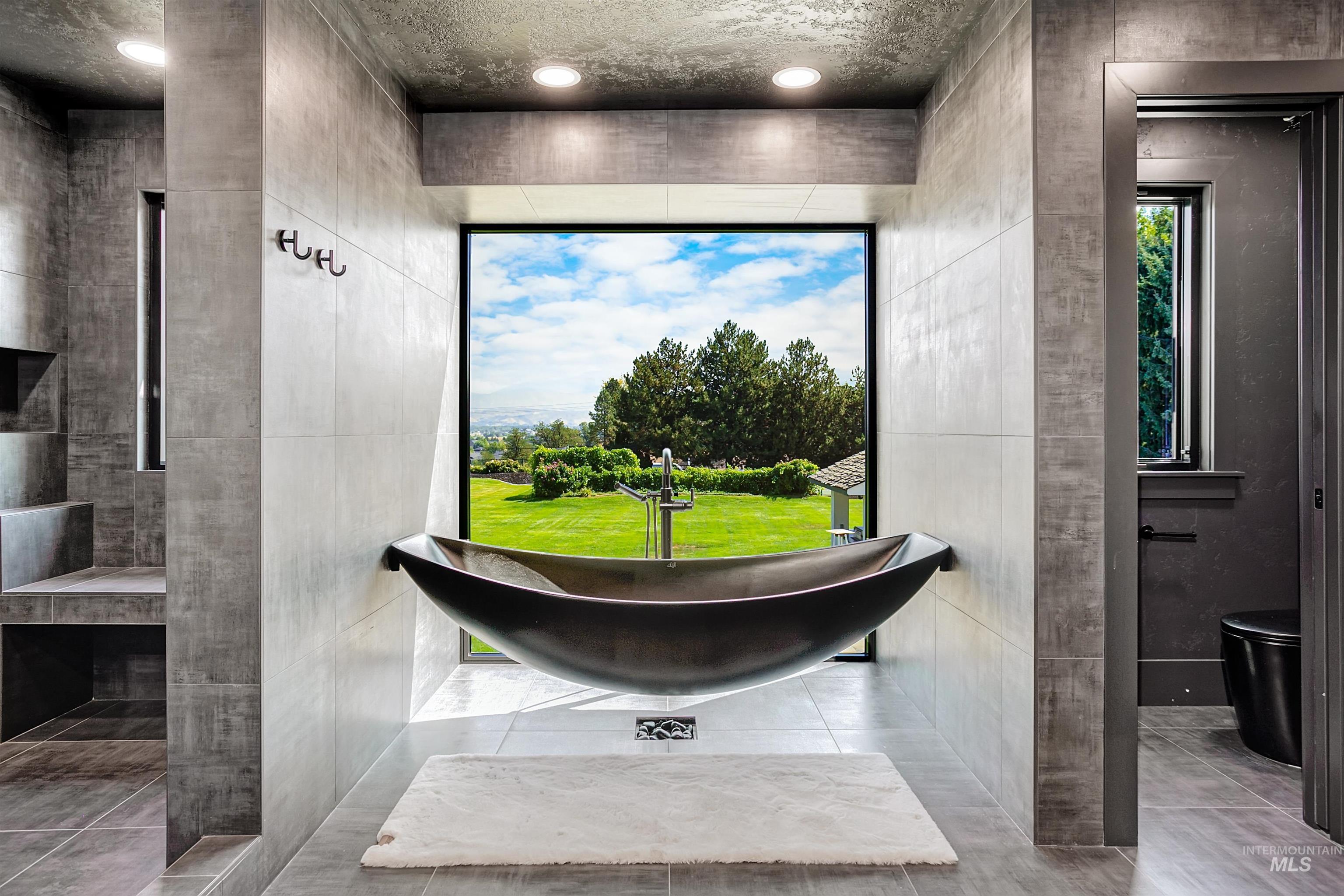 Master bathroom with a freestanding tub, sweeping outdoor view, recessed lighting, and light tile patterned floors.