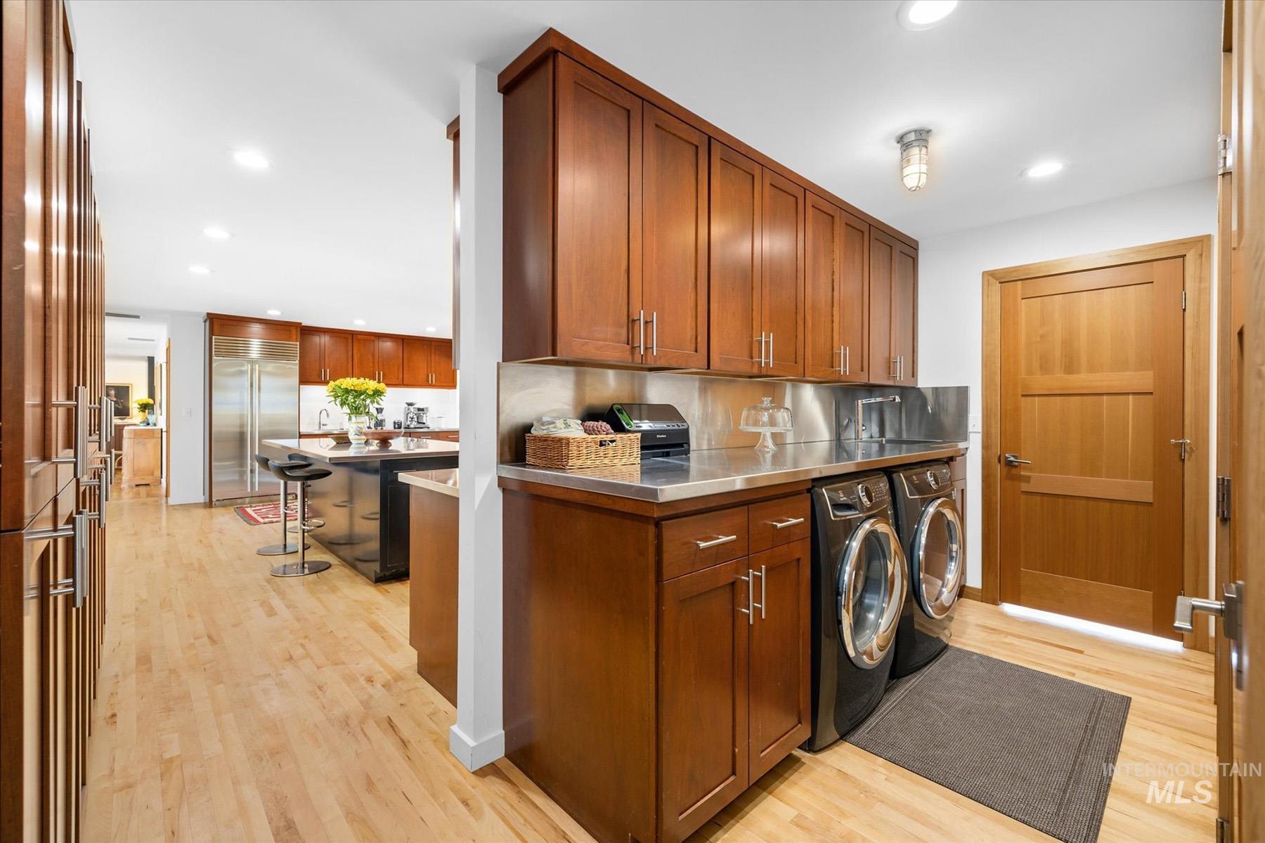 Laundry room featuring washer and clothes dryer, cabinet space, light wood-type flooring, and recessed lighting