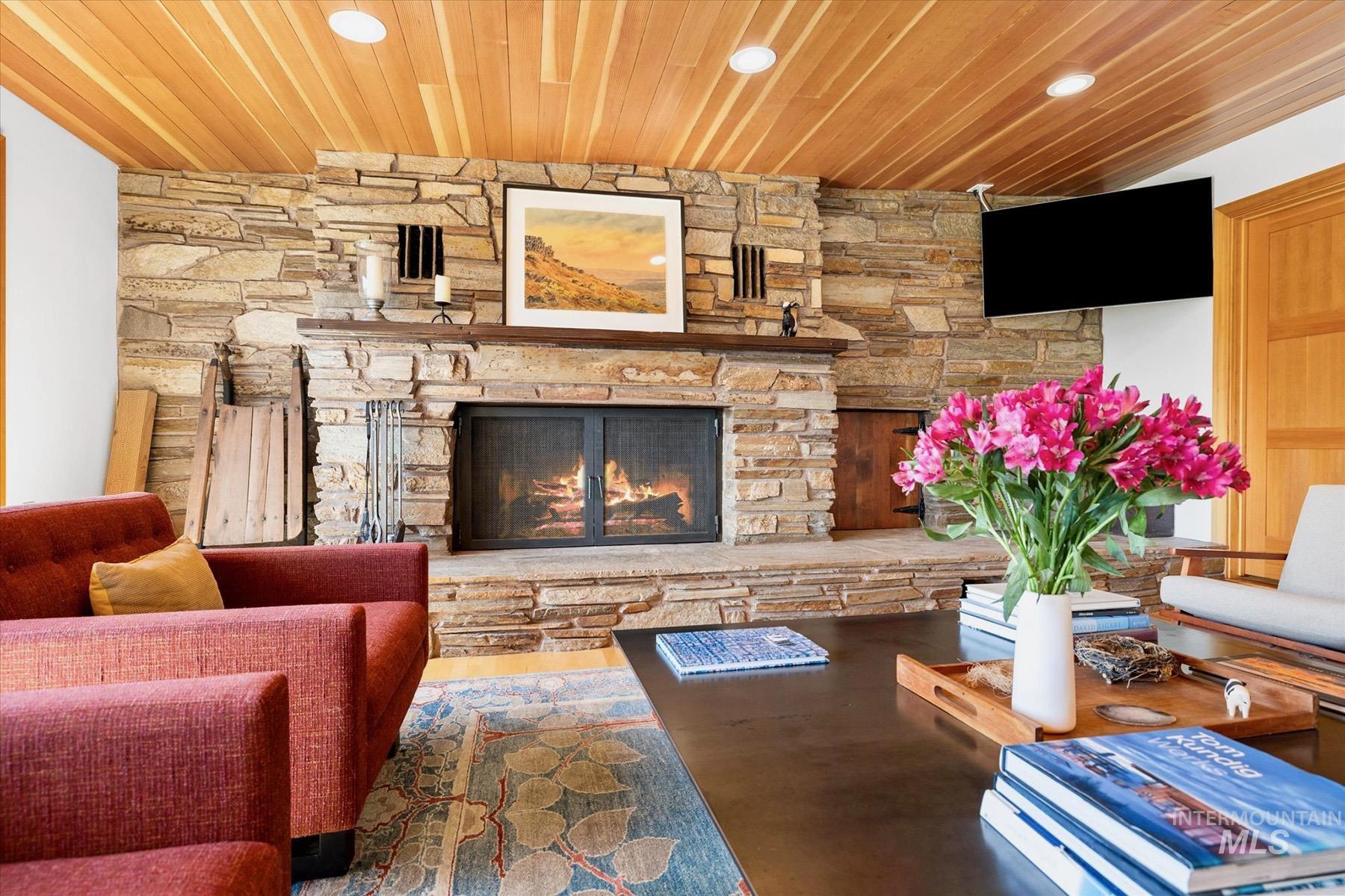 Living room featuring wood ceiling, recessed lighting, and a stone fireplace