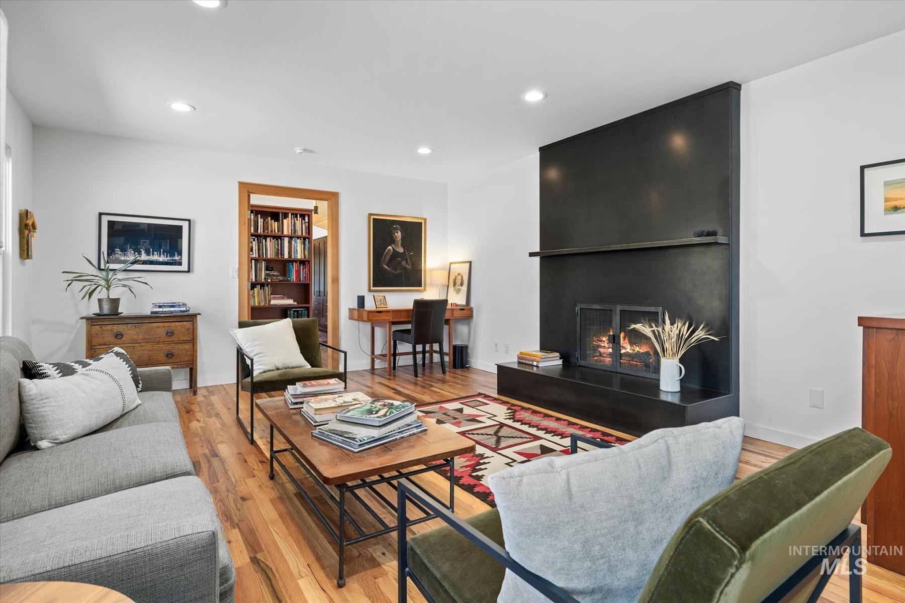 Living room with light wood finished floors, a large fireplace, and recessed lighting