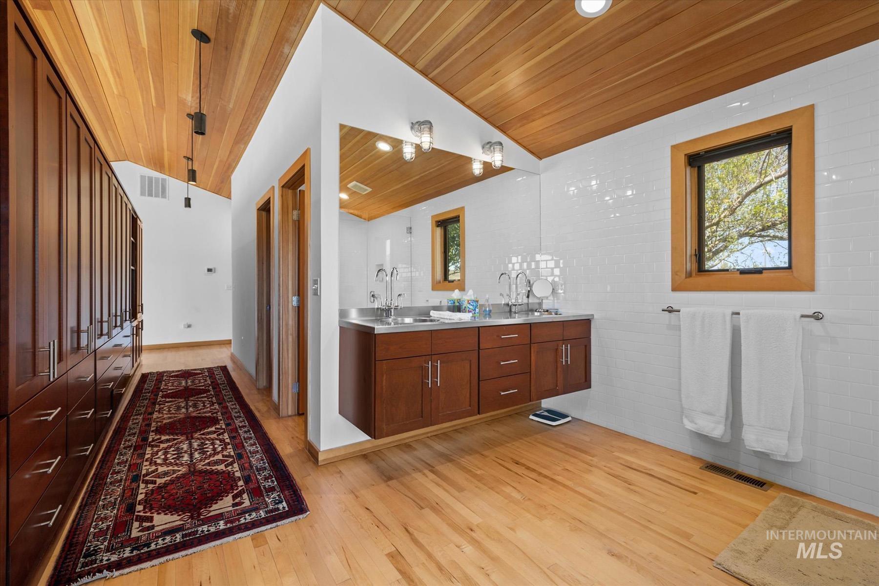 Bathroom with wooden ceiling, wood finished floors, double vanity, and lofted ceiling