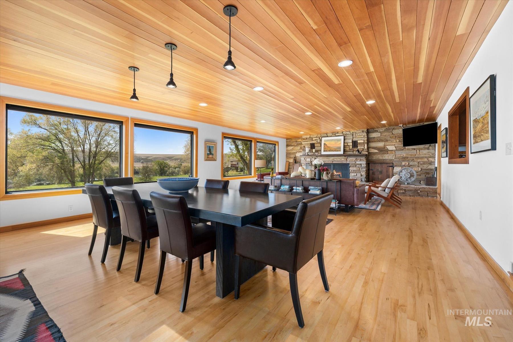 Dining area with wood ceiling, a fireplace, light wood finished floors, and recessed lighting