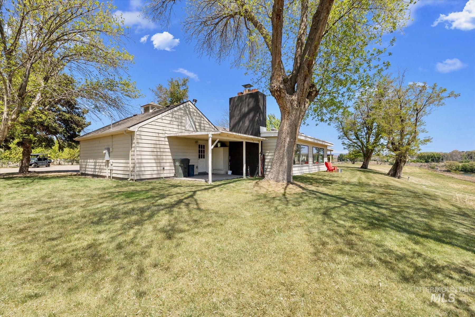 Rear view of property featuring a chimney, a patio, and a lawn
