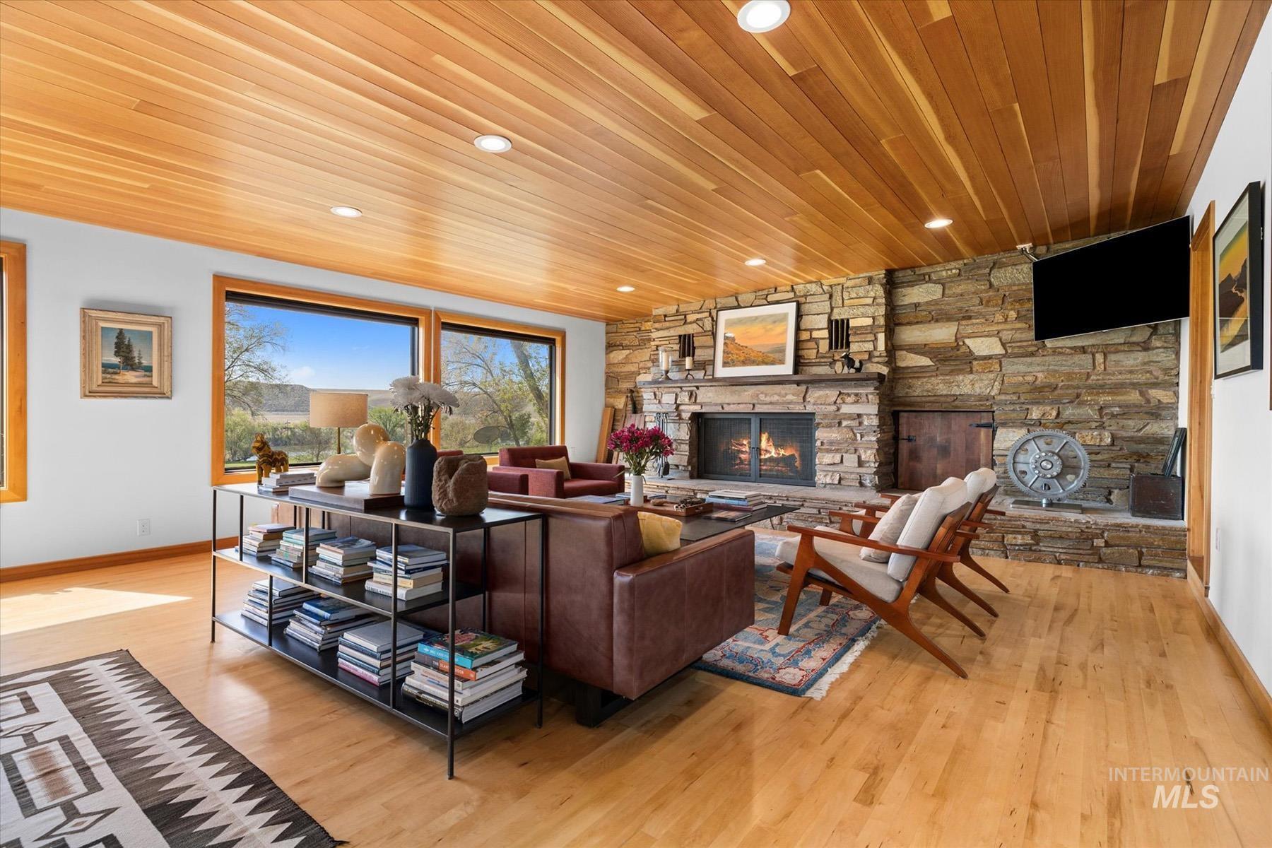 Living area featuring a stone fireplace, wood ceiling, wood finished floors, and recessed lighting