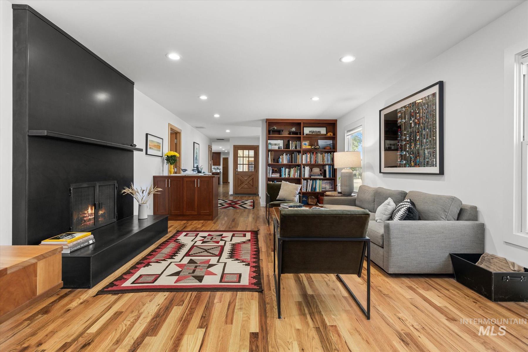 Living room with light wood finished floors, recessed lighting, and a fireplace