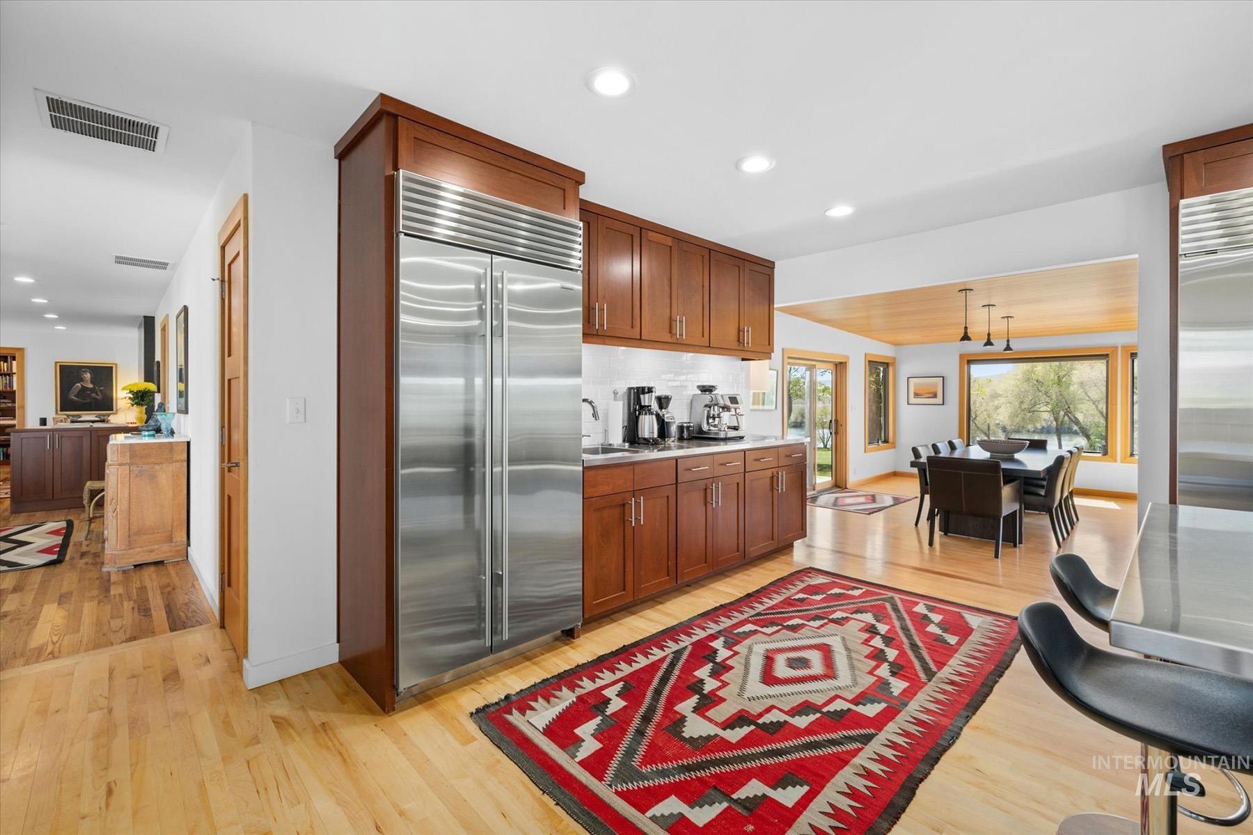 Kitchen with built in fridge, light wood-style floors, light countertops, recessed lighting, and brown cabinets