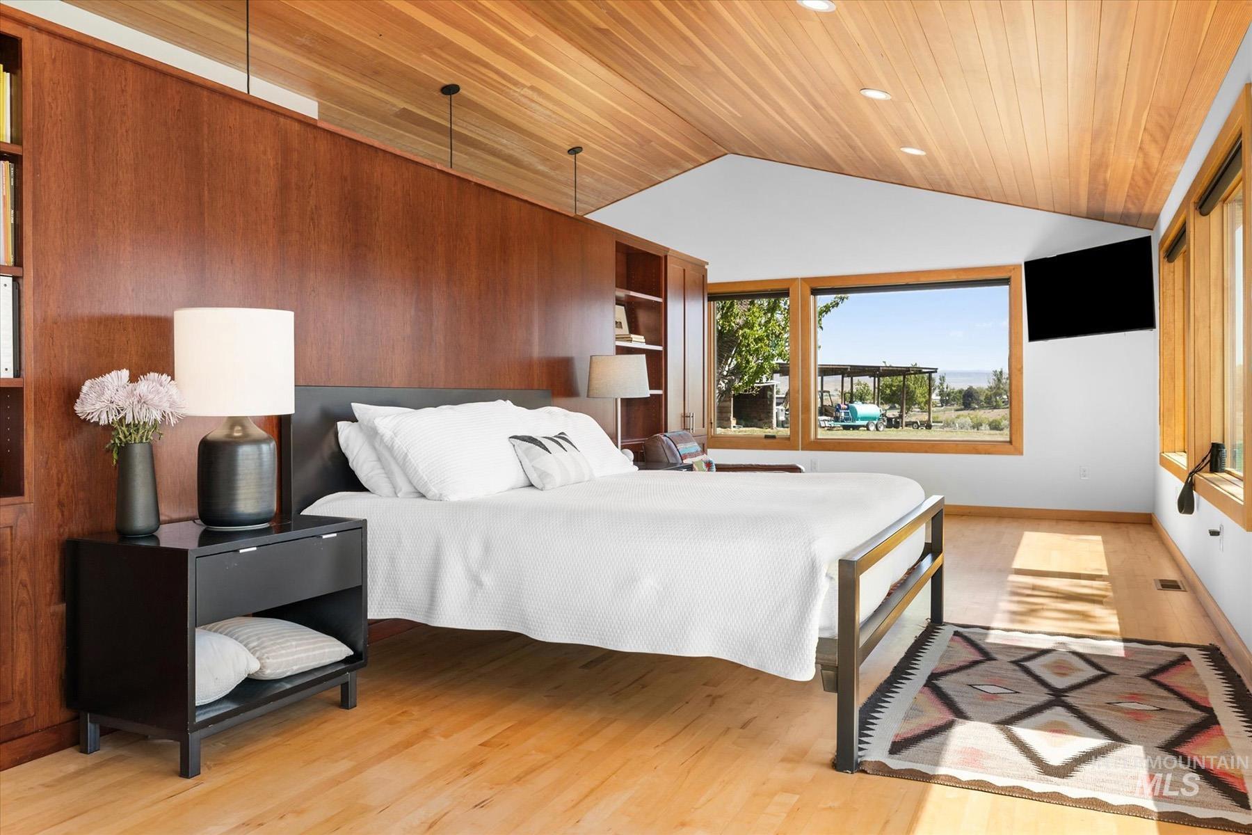 Bedroom with wooden ceiling, vaulted ceiling, and light wood finished floors