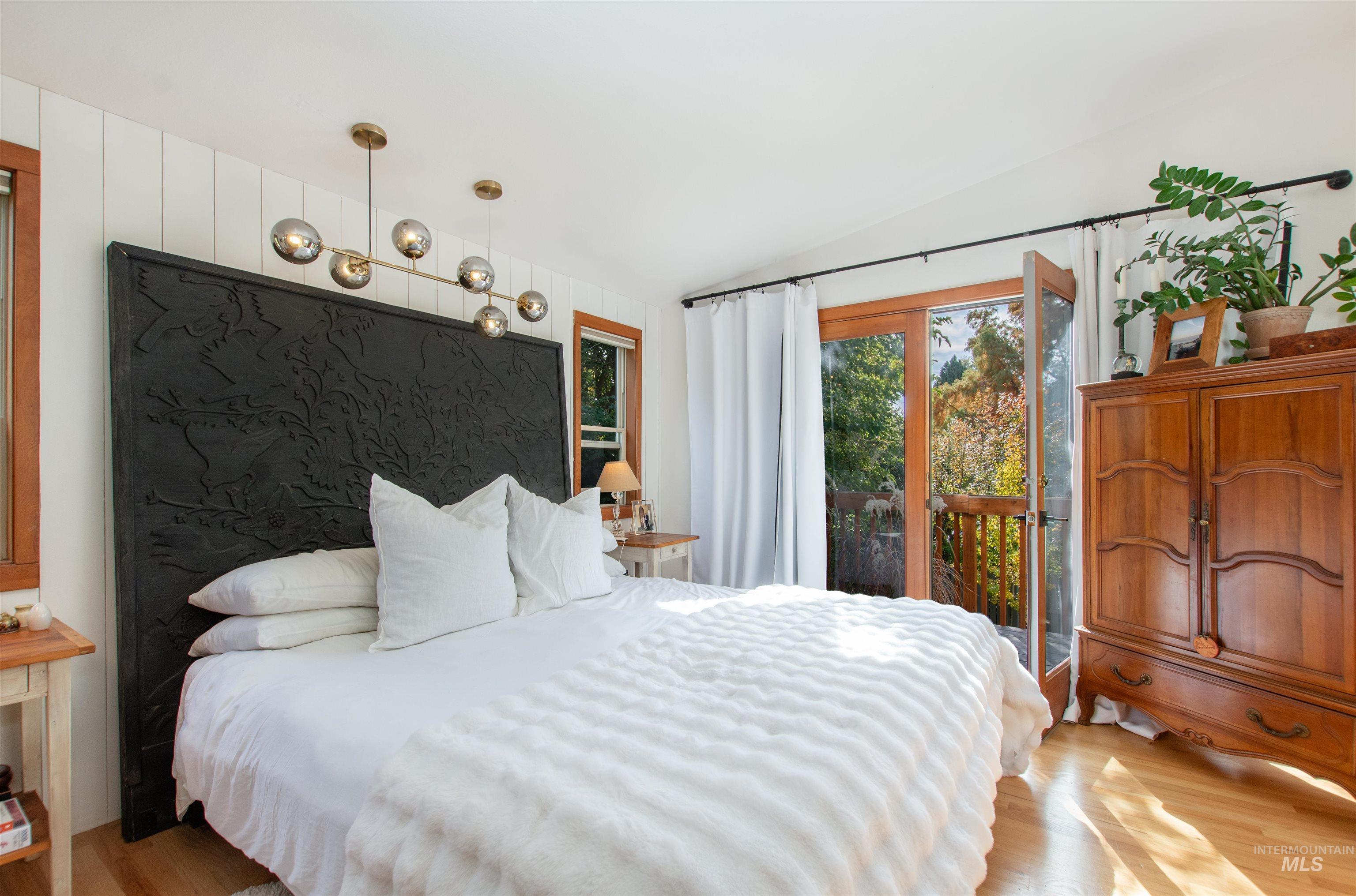 Bedroom featuring wood finished floors, vaulted ceiling, and access to exterior