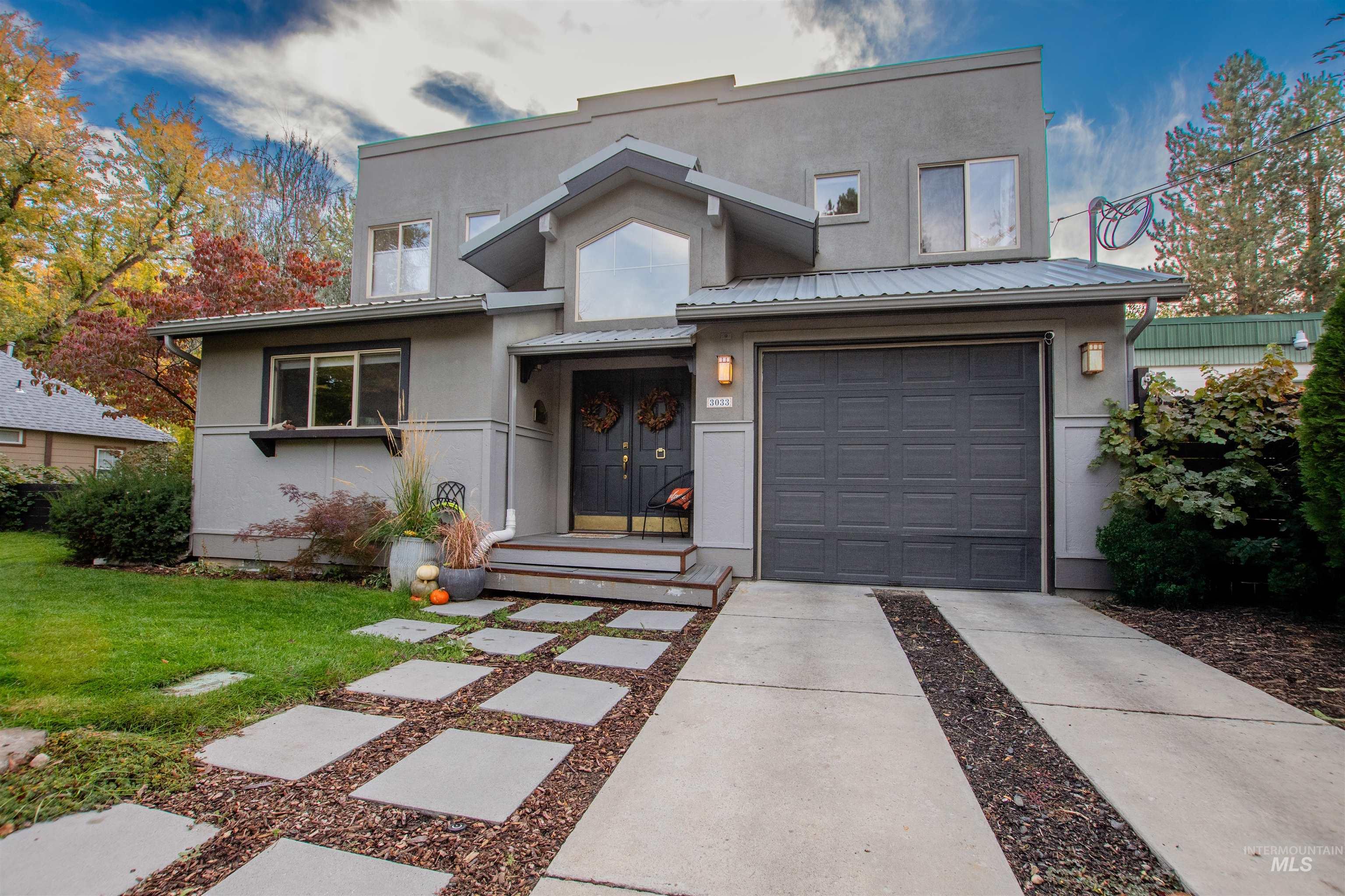 View of front of home featuring a metal roof, concrete driveway, stucco siding, and a front lawn