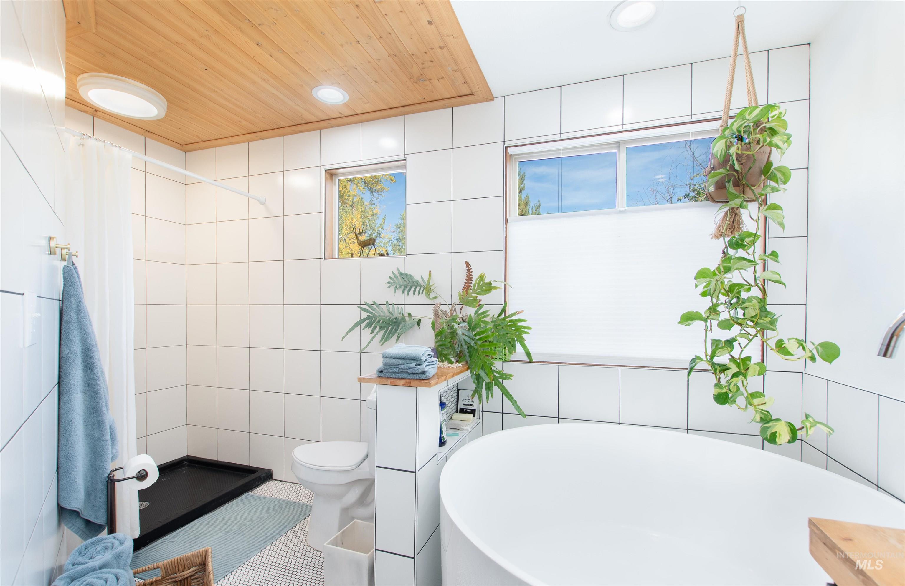 Full bathroom with a freestanding tub, a shower stall, tile walls, recessed lighting, and wood ceiling