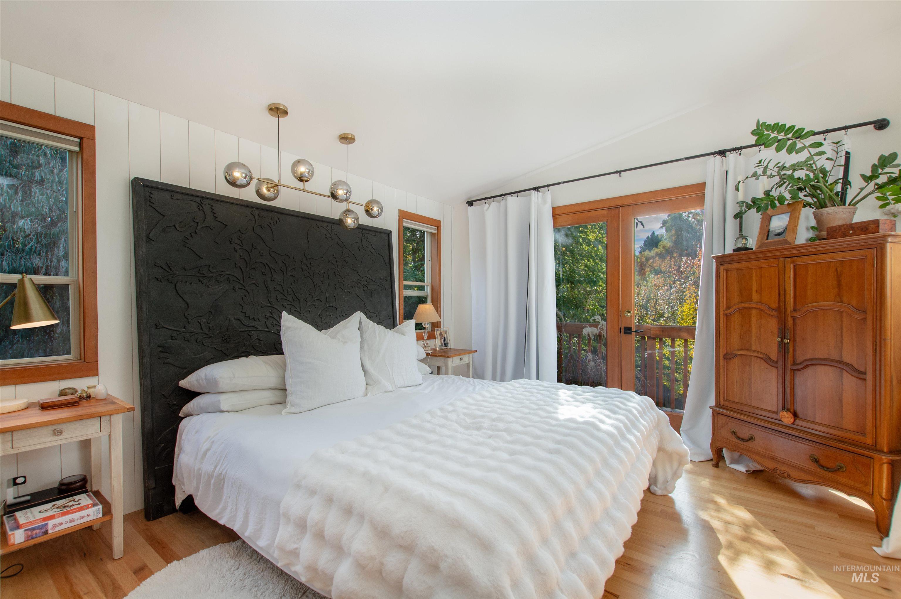 Bedroom with light wood-style flooring, access to outside, vaulted ceiling, and french doors