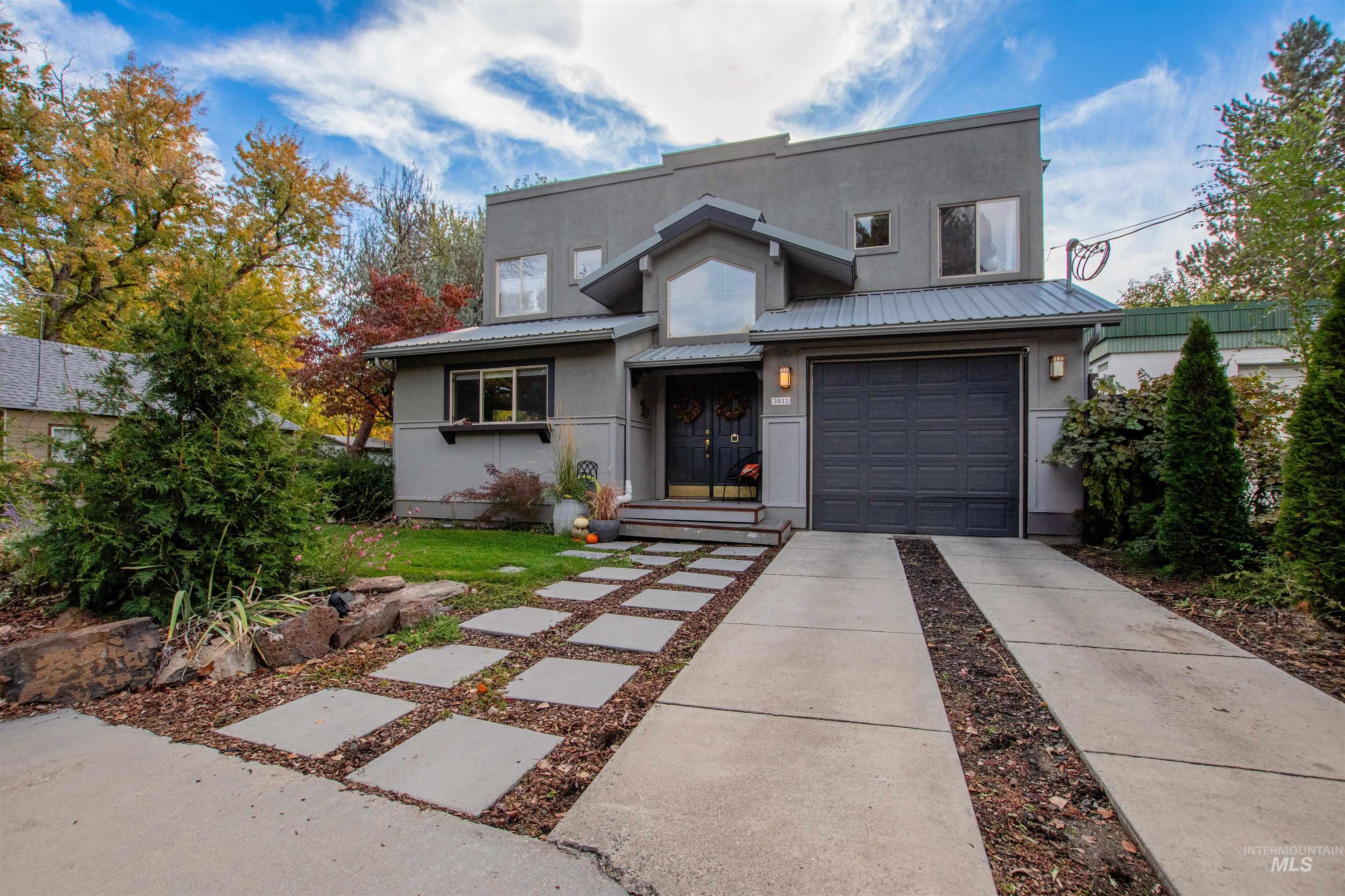View of front facade with a metal roof, concrete driveway, stucco siding, and an attached garage