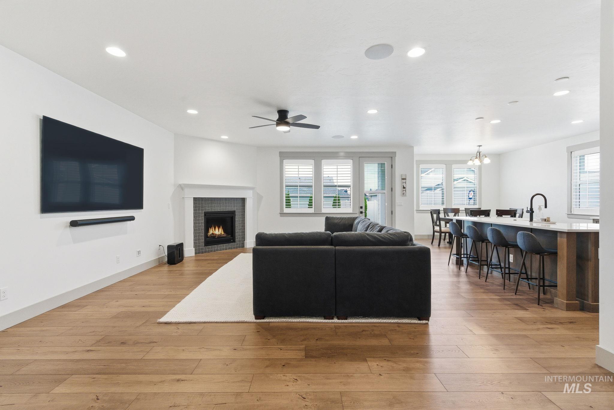 Living area with plenty of natural light, a warm lit fireplace, light wood finished floors, and recessed lighting