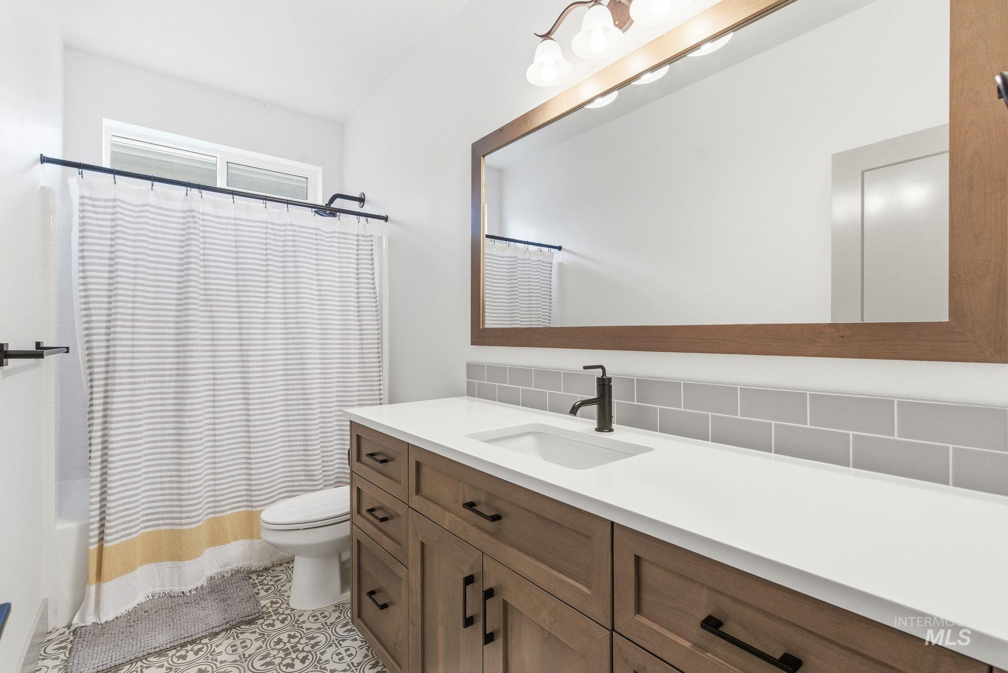 Bathroom featuring vanity, tasteful backsplash, light tile patterned floors, and shower / bath combo