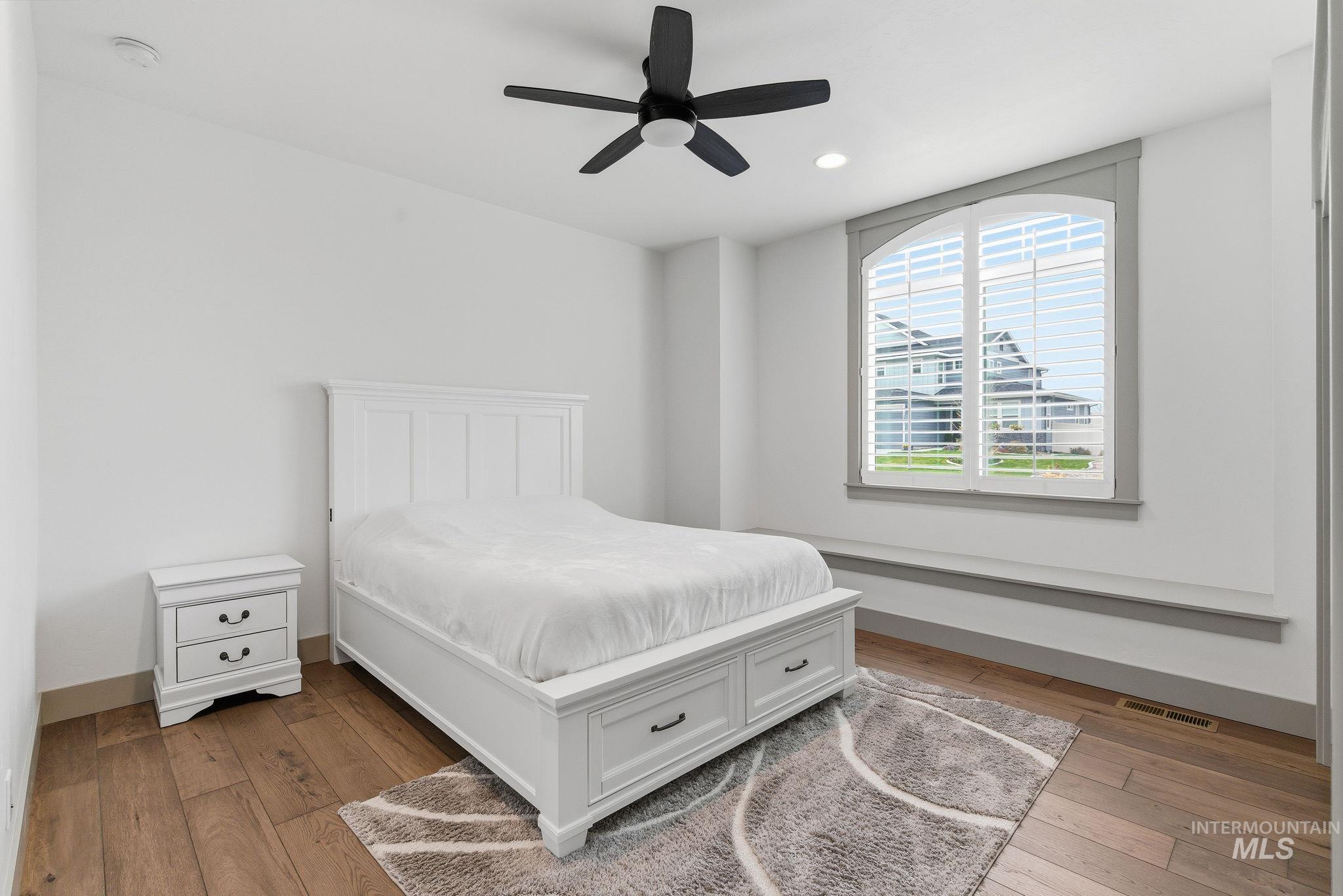 Bedroom with light wood finished floors, ceiling fan, and recessed lighting