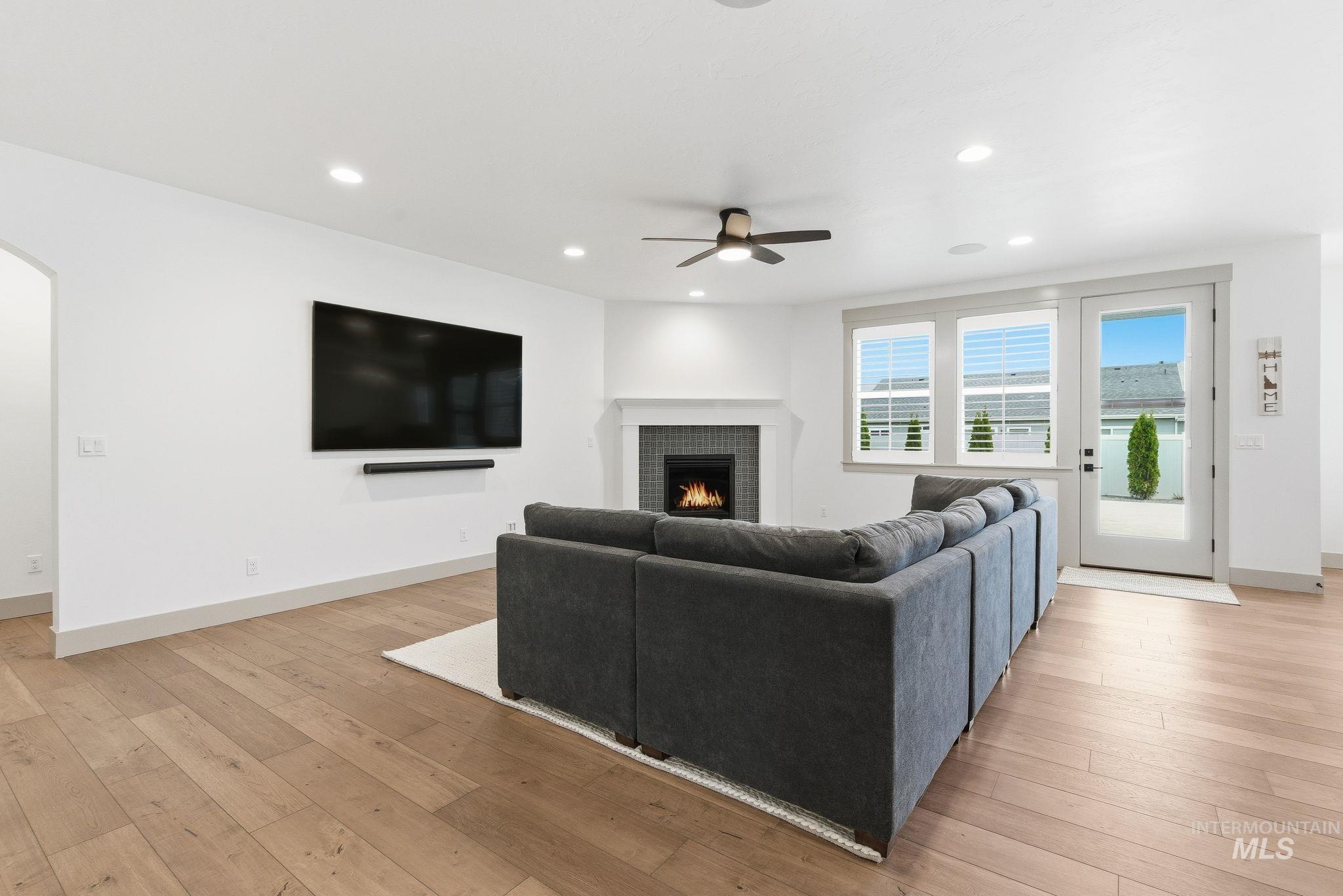 Living room with recessed lighting, light wood-type flooring, a fireplace, arched walkways, and ceiling fan