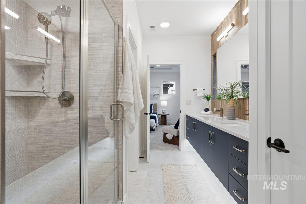 Full bath featuring double vanity, ensuite bath, a shower stall, and recessed lighting