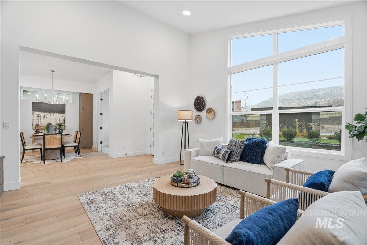 Living room with light wood finished floors, a towering ceiling, a chandelier, and recessed lighting