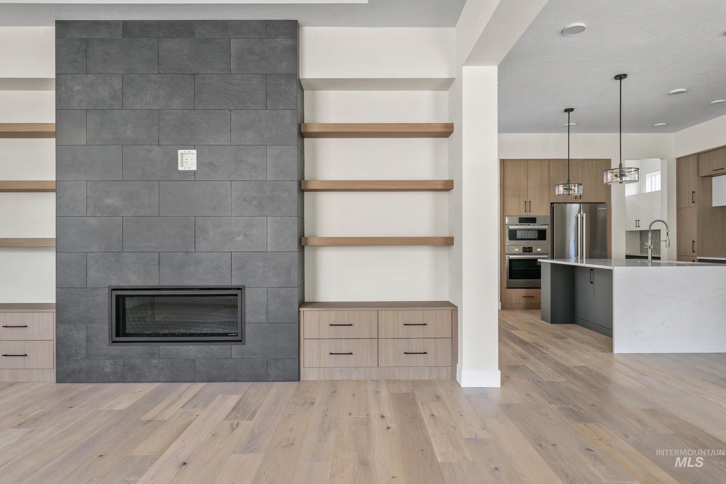Unfurnished living room with light wood finished floors and a large fireplace