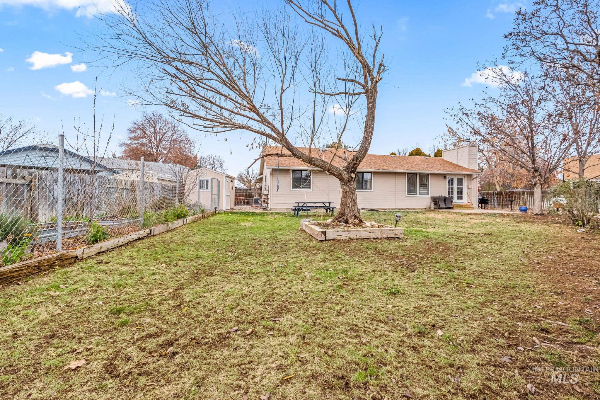 Back of house featuring a fenced backyard, a vegetable garden, a patio area, and a chimney