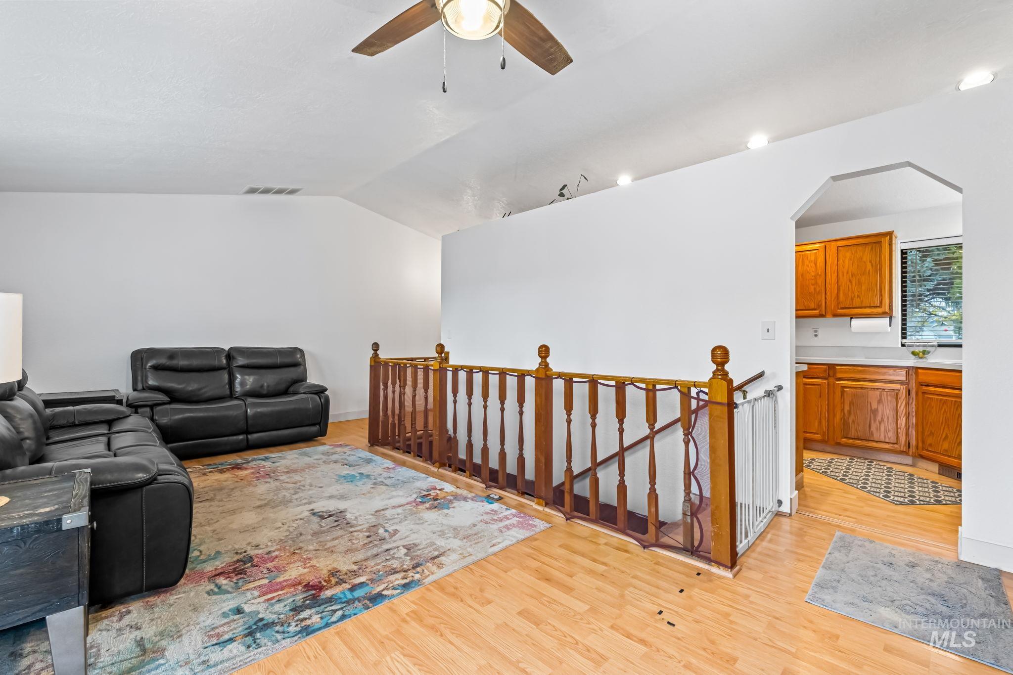 Living room featuring light wood finished floors, vaulted ceiling, and ceiling fan
