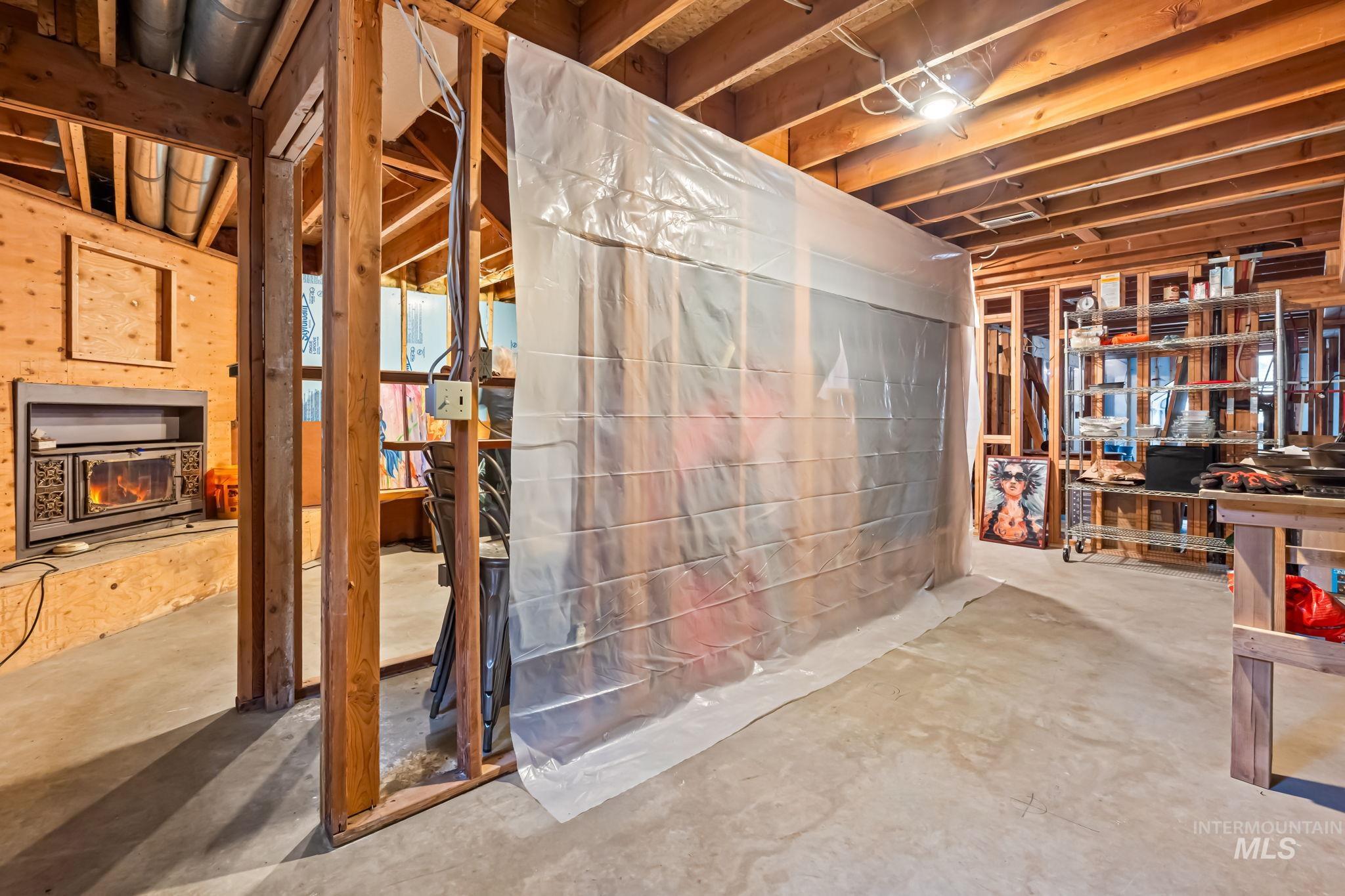 Unfinished basement featuring a lit fireplace