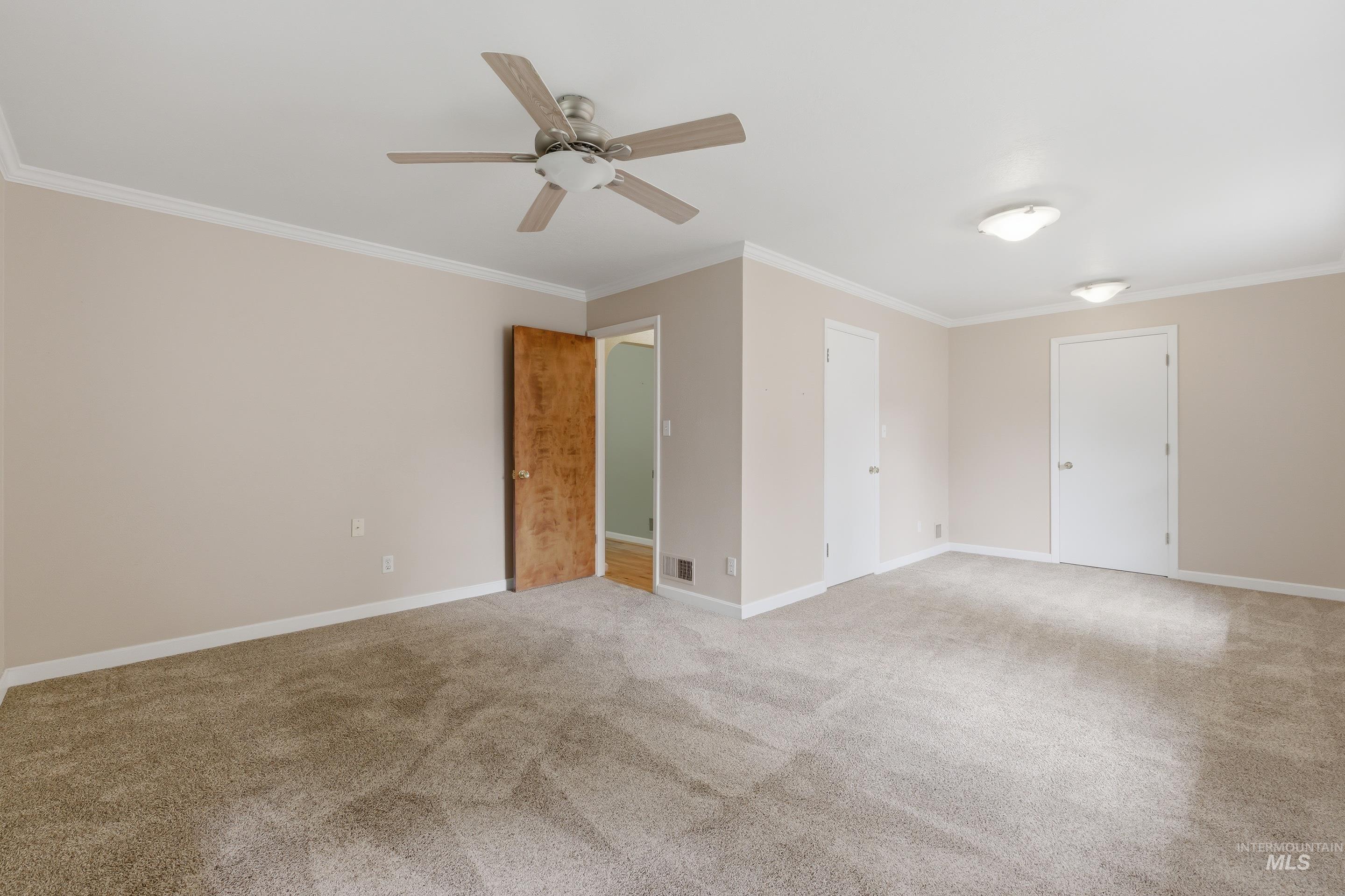 Spacious room featuring neutral carpeting, a ceiling fan with light, and multiple flush-mount light fixtures
