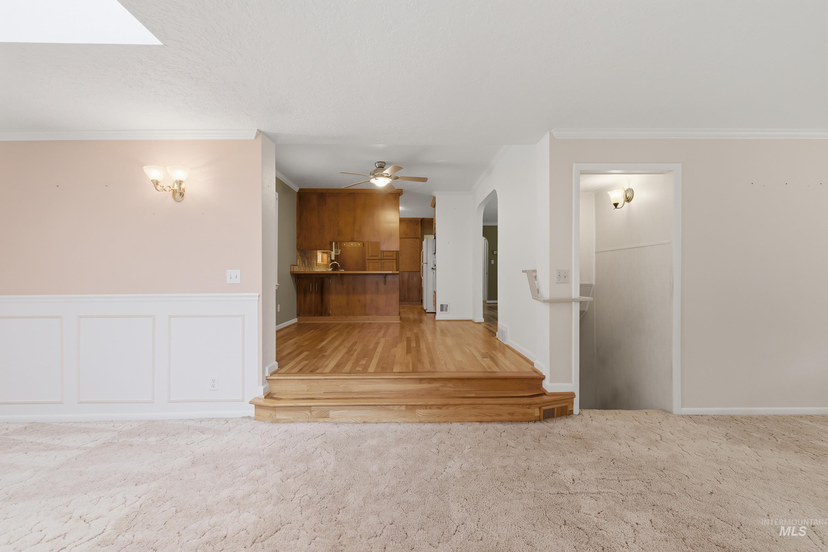 Carpeted living area with wainscoting and wall sconces