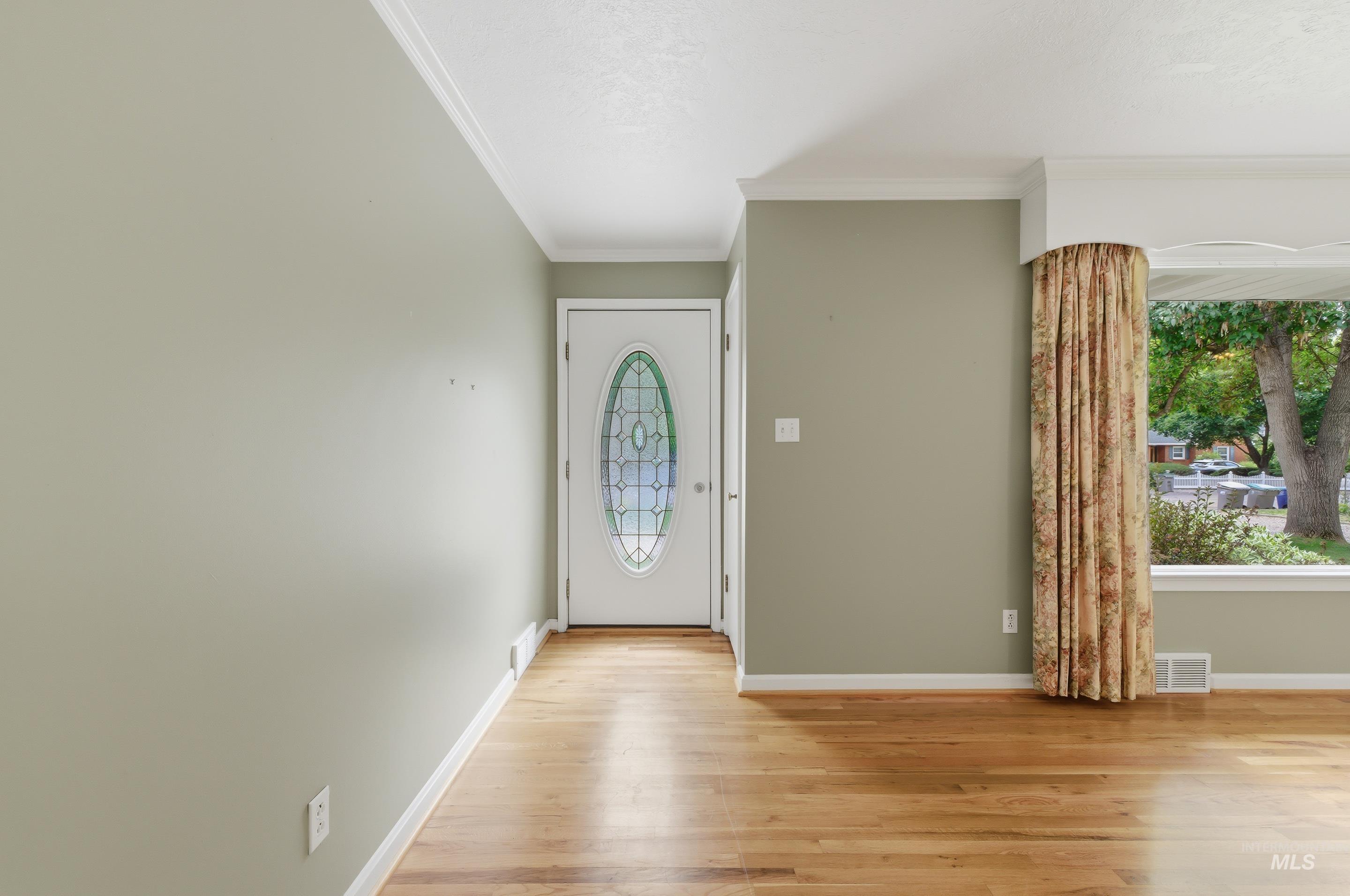 Entryway featuring a decorative oval-lite door, light hardwood flooring, and a bay window